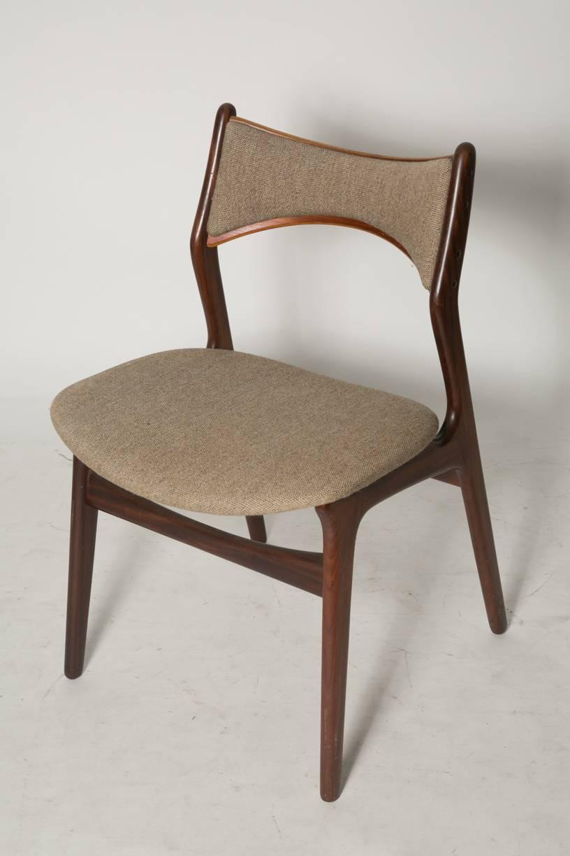 Set of four Erik Buck stylized model #310 dining chairs. The frame is made of teak and the chairs are covered by an elegant neutral wool fabric. This set is a rare find with the padded backrest not often seen. The all original chairs show only very