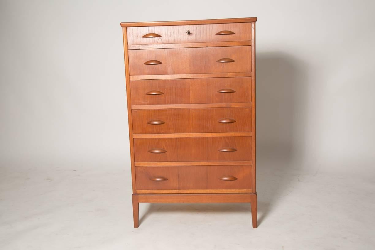 Beautiful chest by Kai Kristiansen features tapered square legs integrated in the chest frame. The dresser comes with an locked top drawer. Key is of brass. The dresser slender shape and appearance is complimented by elliptical pulls. This piece is