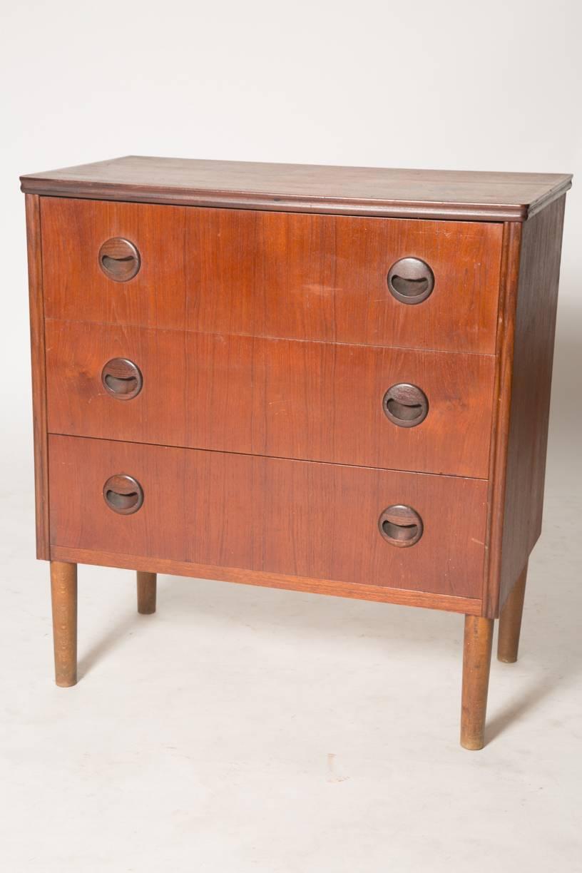 Teak bachelor chest with three drawers in the style of Kai Kristiansen. Nice eyelid shaped pulls on this piece and fine carving work on the trim. Would also be prefect as a nightstand. Produced in the 1960s. Good vintage condition.
 
