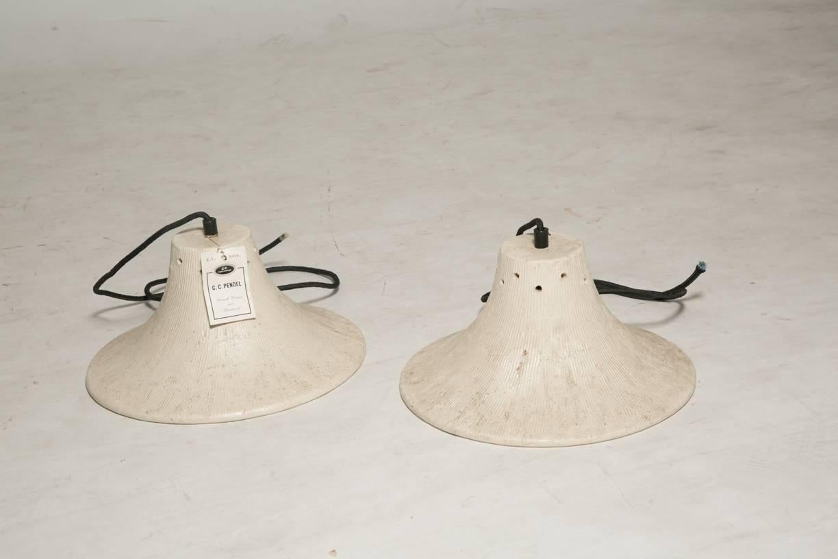 Vintage studio pottery stoneware light fixtures. a pair each in bone and earth with red enameled interiors. These lights are dead stock never installed with tags in place. Elegant and rustic elements combine in these attractive pendants. Bone
