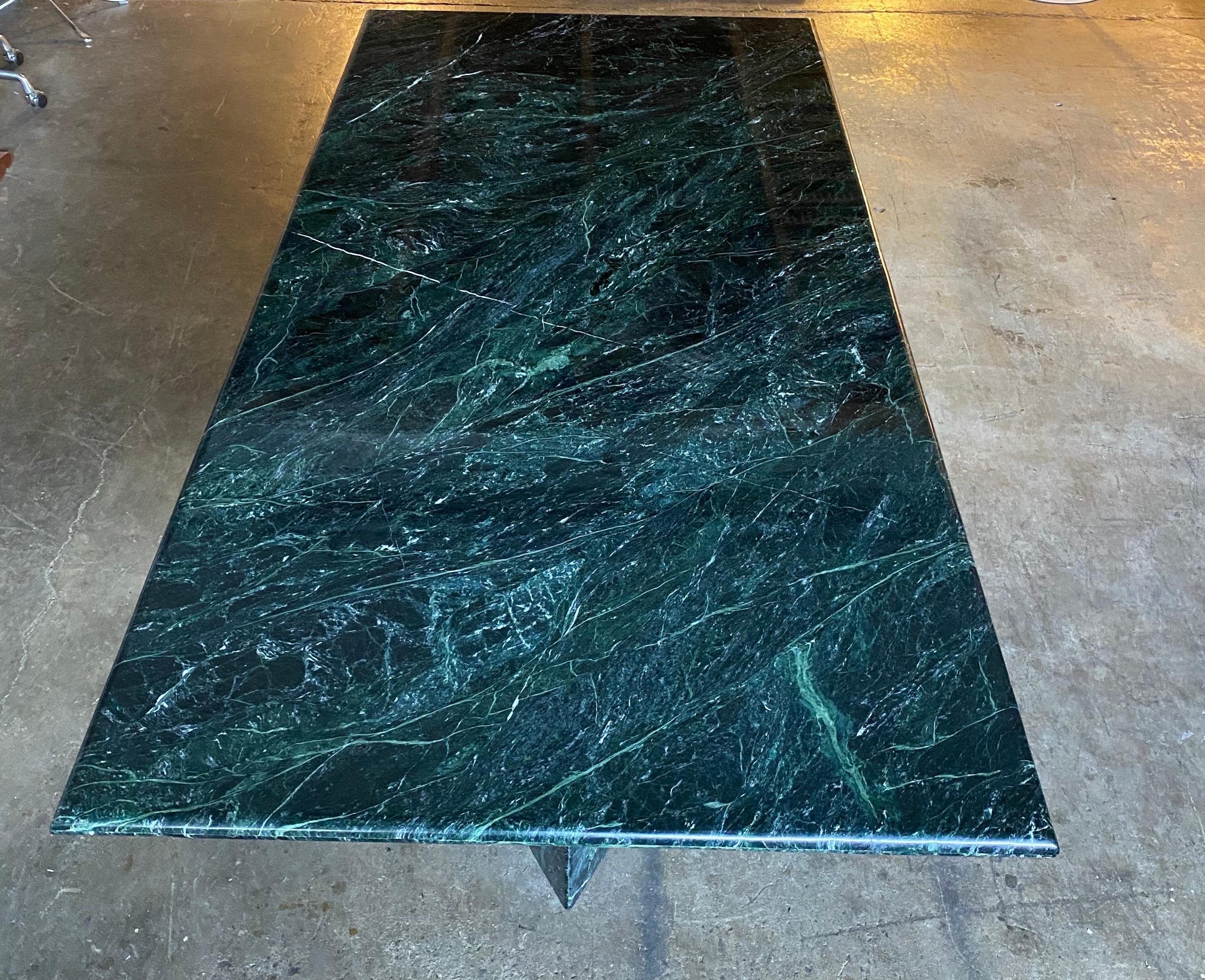 Incredible dining table in green marble. Rectangular shape allows for 10 dining chairs. Bullnose edge softens the sides and creates a stunning effect. No dings or fading. Marble in good condition. Top rests upon triangular marble pedestals of the