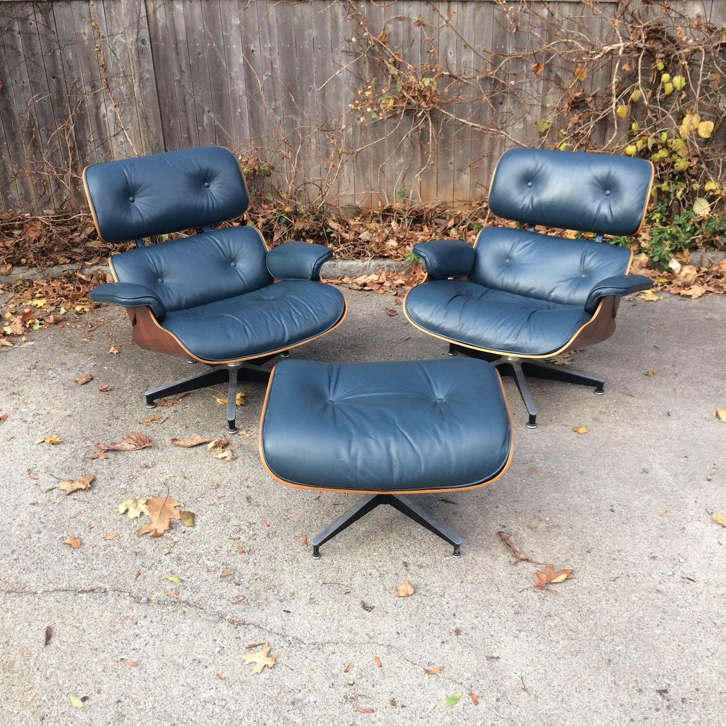 1970s Herman Miller Eames lounge set. Two chairs and one ottoman in custom blue leather and Brazilian rosewood. The shells on the chair have been beautifully restored. The leather is original and perfect. Foam cushions with rectangular clips. Both