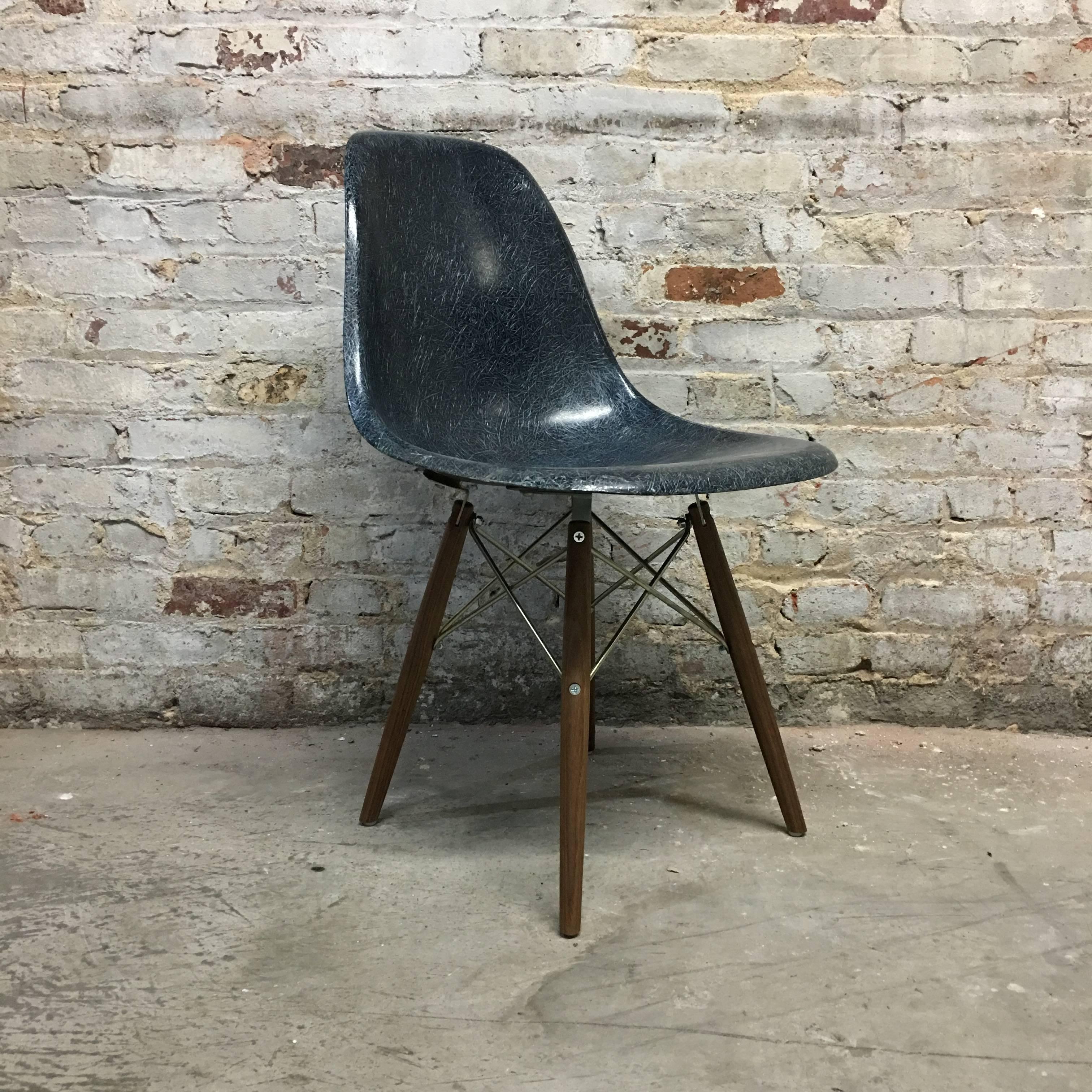 Set of eight Herman Miller Eames fiberglass dining chair in rare navy blue color. New doel bases in walnut (or maple or birch). Metal available in zinc (pictured) or black. Chairs boast wonderful fibers and deep color with no cracks or fading.