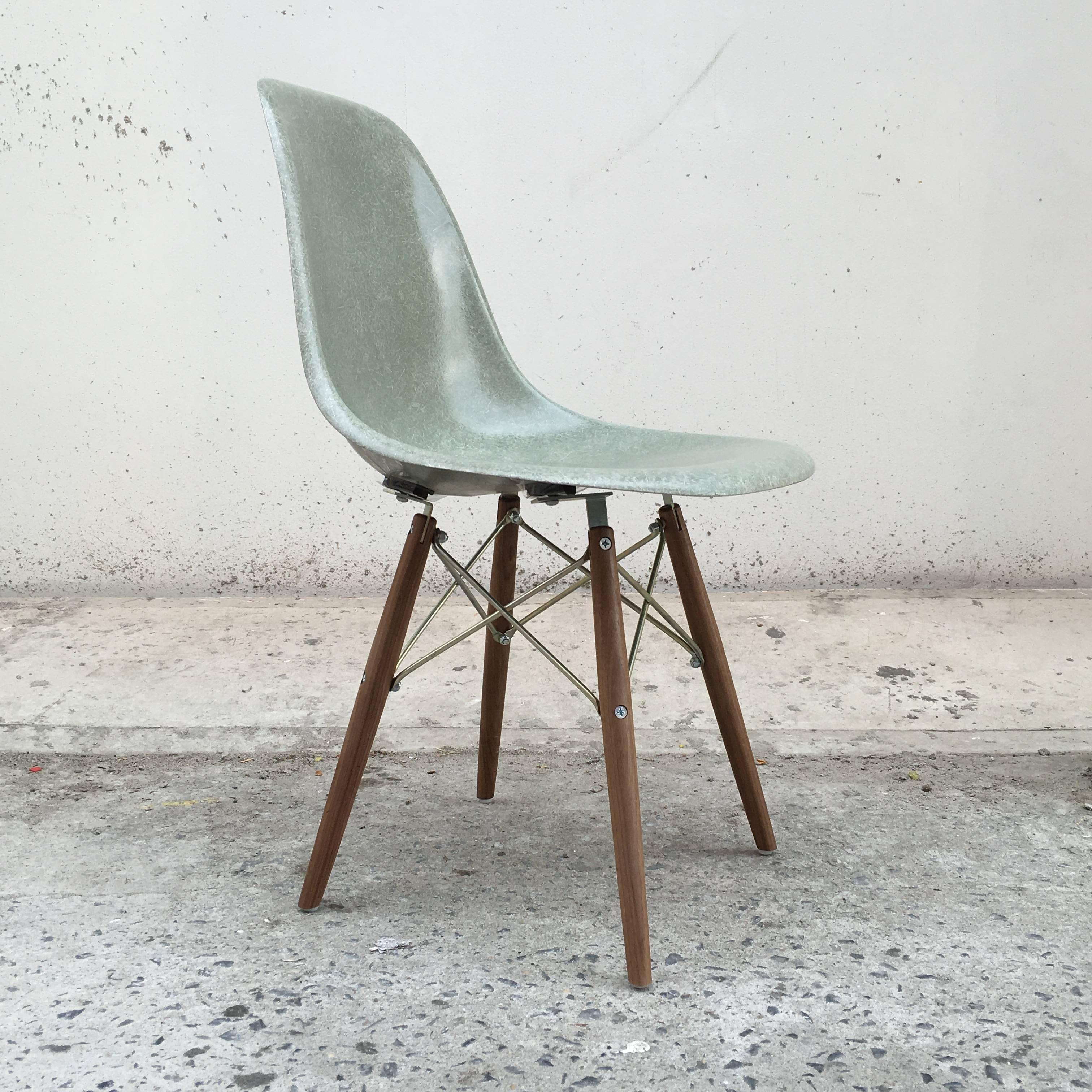 Four Herman Miller Eames dining chairs in rare seafoam green. New walnut dowel bases from Modern Conscience. Chairs have excellent color with no cracks or holes.