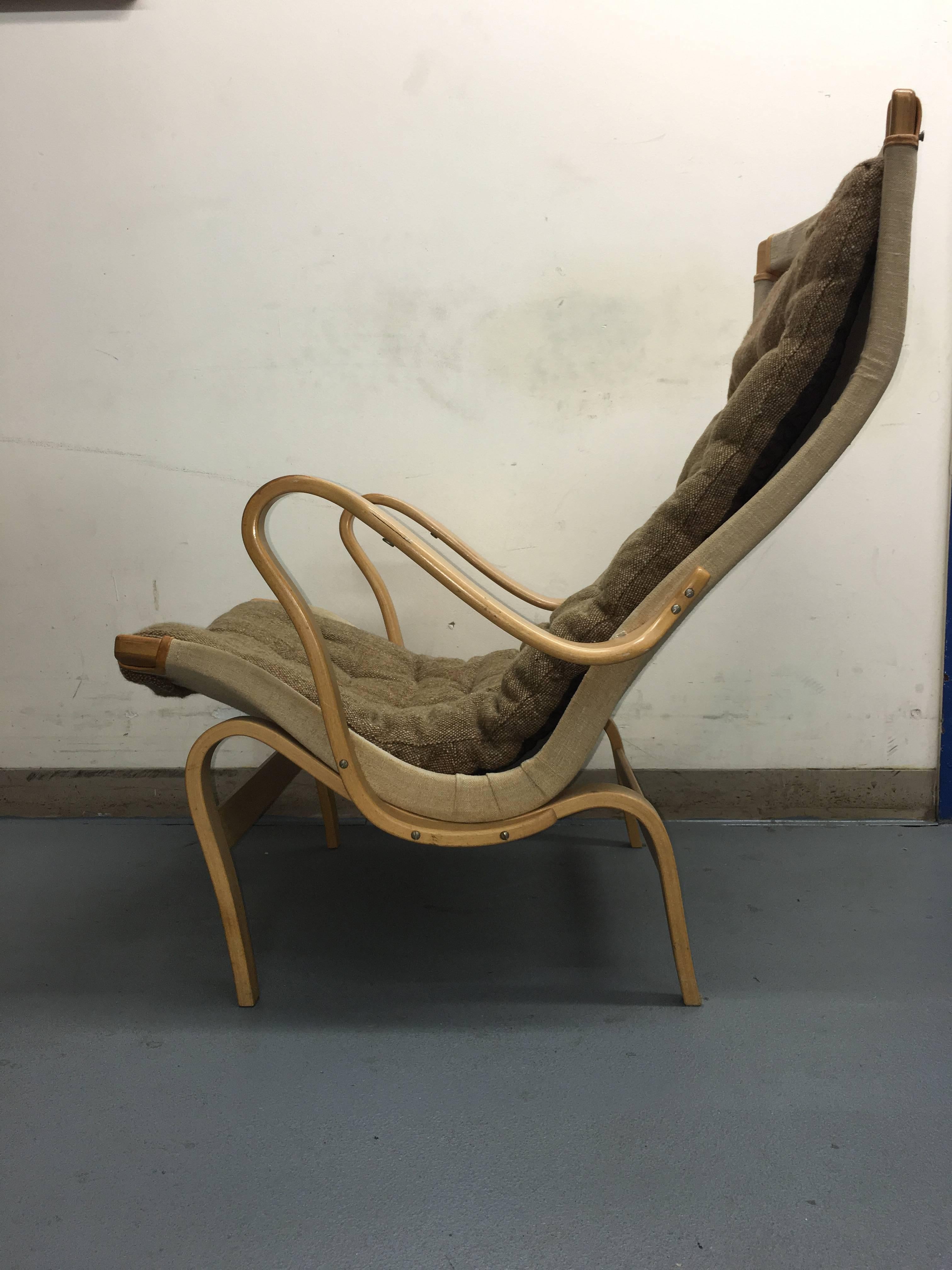 Pernilla lounge chair by Bruno Mathsson for Dux. In good vintage condition. Great wood. Headrest needs to be reattached. It has a piece of the textile missing but that is on the back of the headrest and not visible. Signed and retains tag from