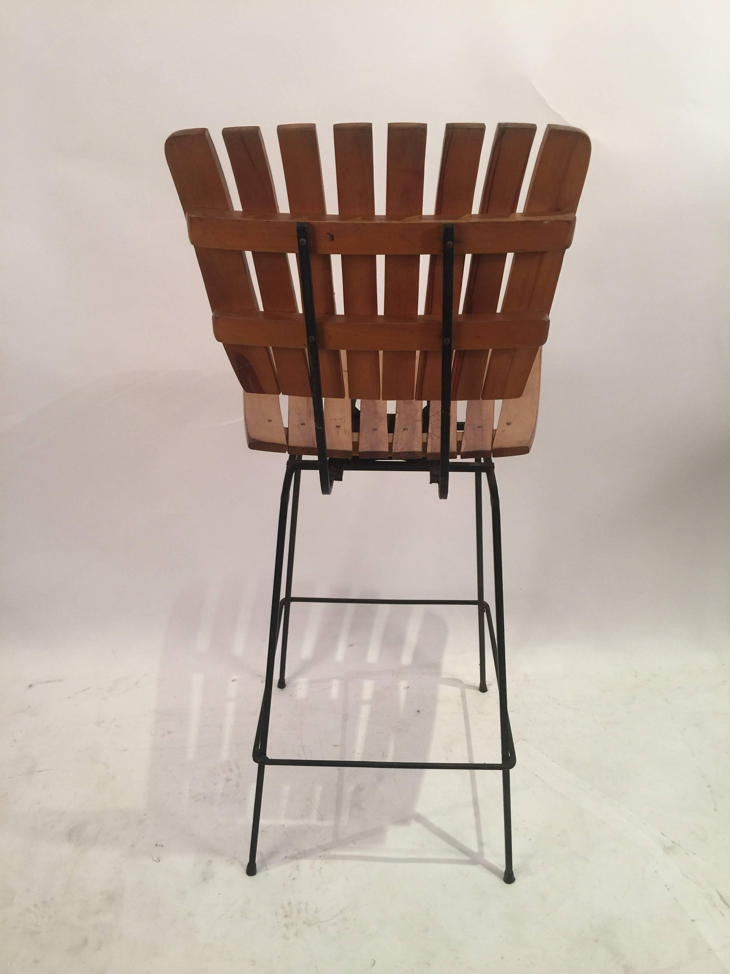 The original Arthur Umanoff slat bar stools produced by Raymor. Consisting of square gage wrought iron and birch wool slats. Stool swivels. Tiki modern.