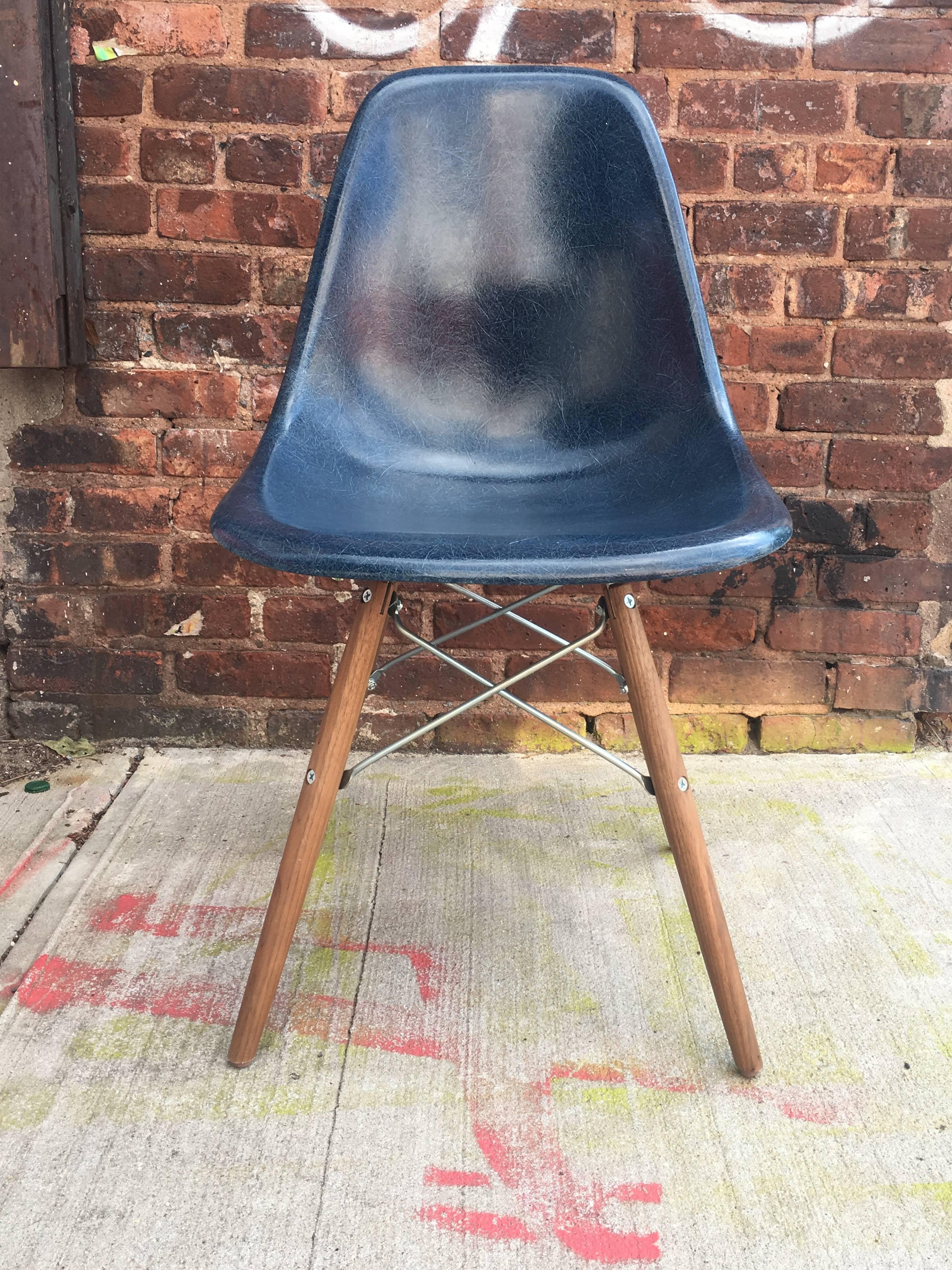 Eight Herman Miller Eames dining chairs in navy and parchment with new walnut bases. In excellent condition. Ships disassembled.