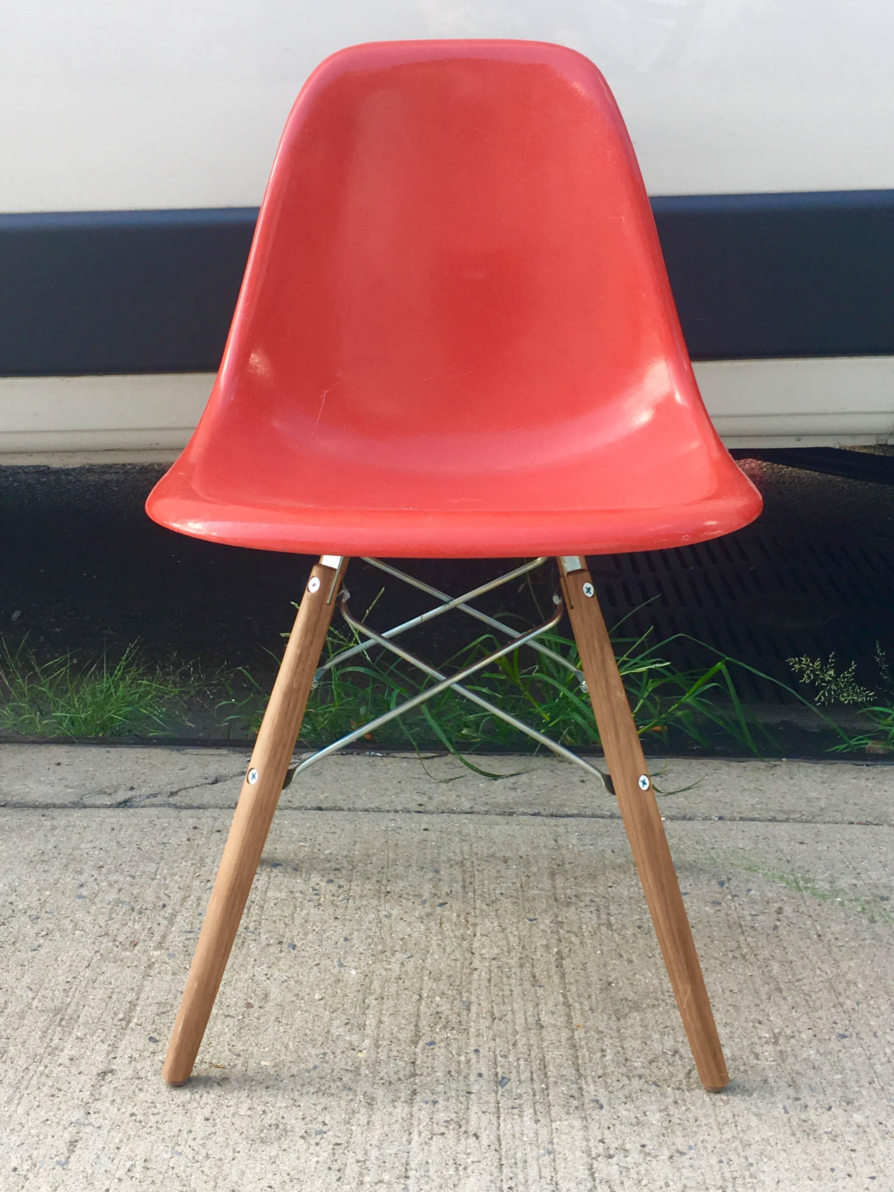 Six multicolored Herman Miller Eames dining chairs on new walnut stained bases. In good condition. One chair with crack along rim. Two red orange, one elephant grey, one cream, one tan, one light yellow. Colors of shells and wooden legs may differ