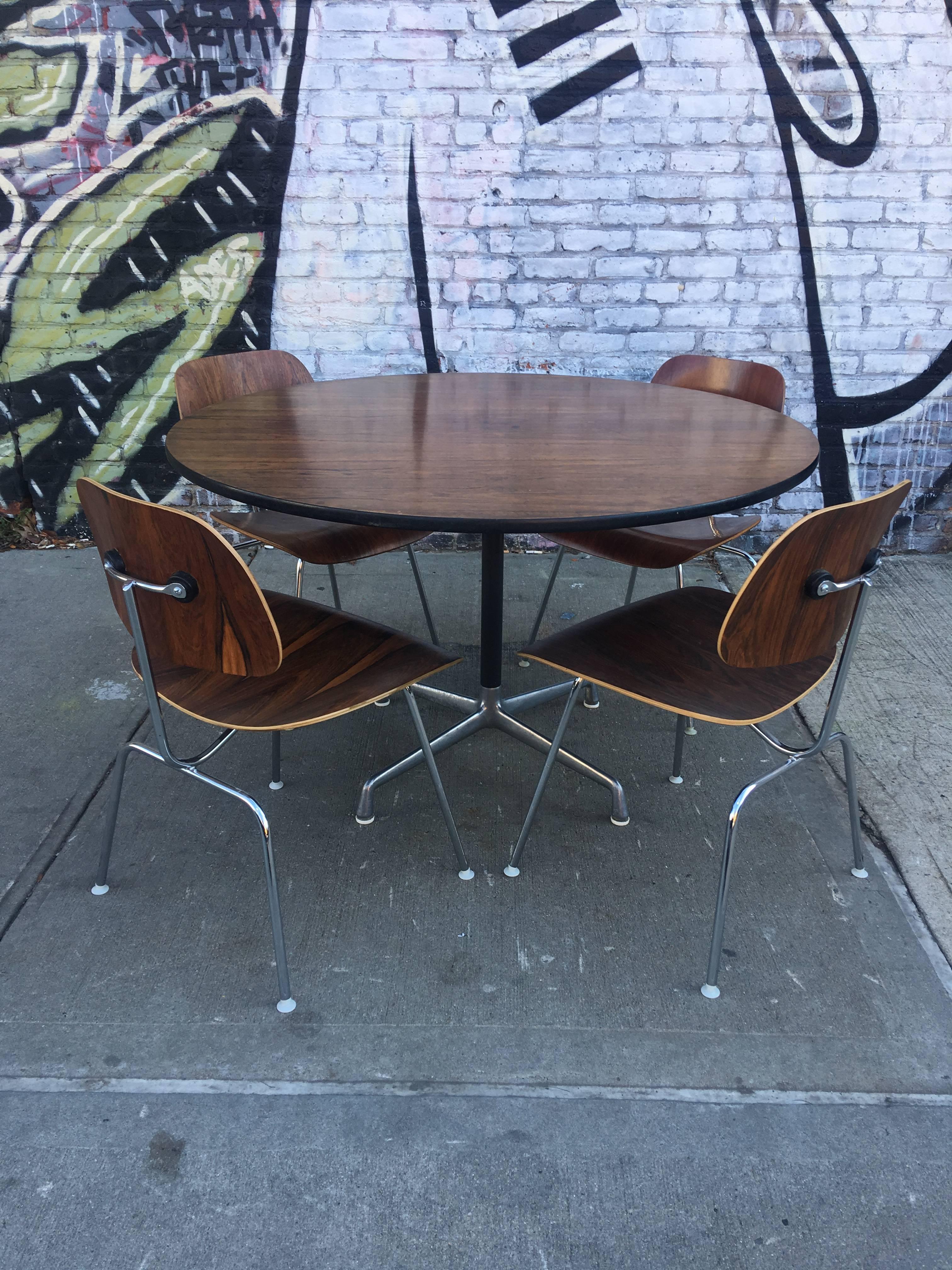 Herman Miller Eames rosewood dining set. Chairs in impeccable condition. Table can accommodate six chairs and we have two additional matching rosewood dining chairs. Table on segmented aluminium base. Table rope in very good vintage condition.