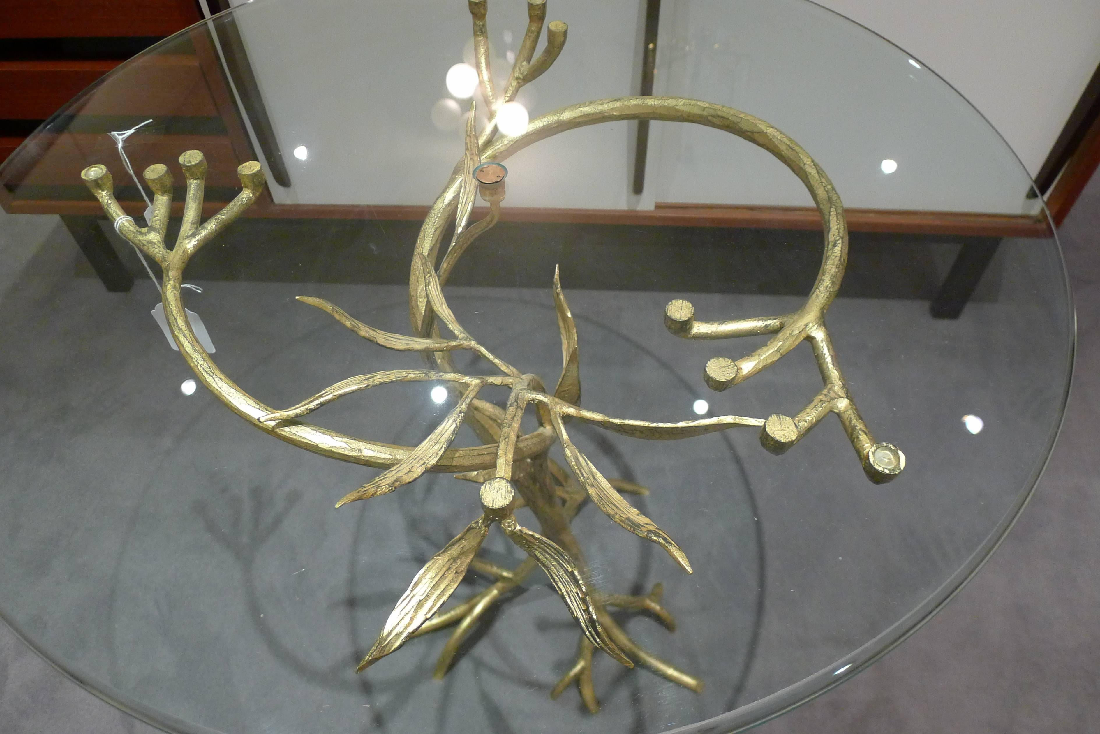 This is a coffee table like a tree. The structure is wrought iron with a gold pattern.
