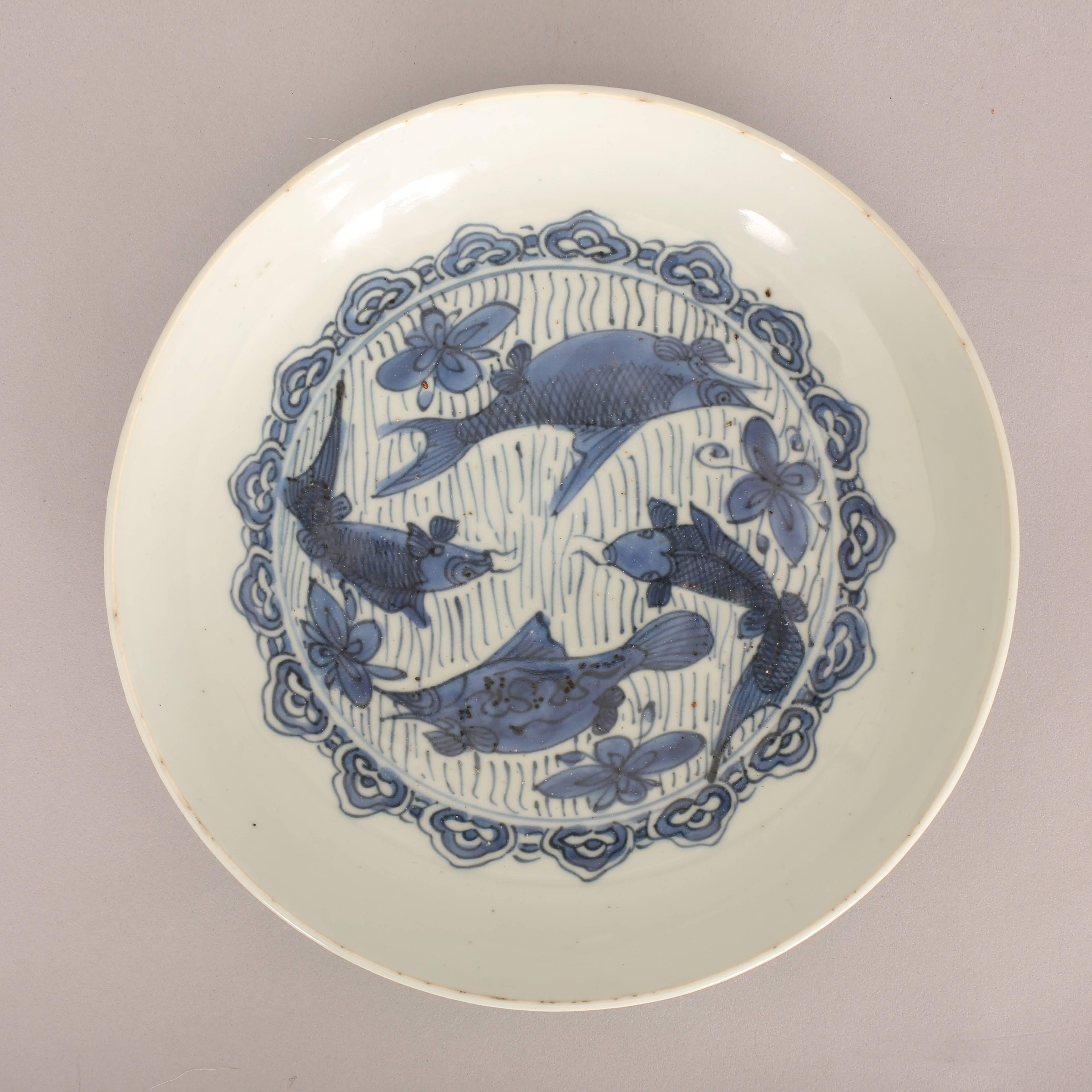 A Chinese export porcelain blue and white saucer dish painted with two perch (mandarin fish) and two carp in water surrounded by aquatic flowers, the medallion surrounded by a continuous decorative ruyi-head border,

Wanli, 1573-1619.

Diameter