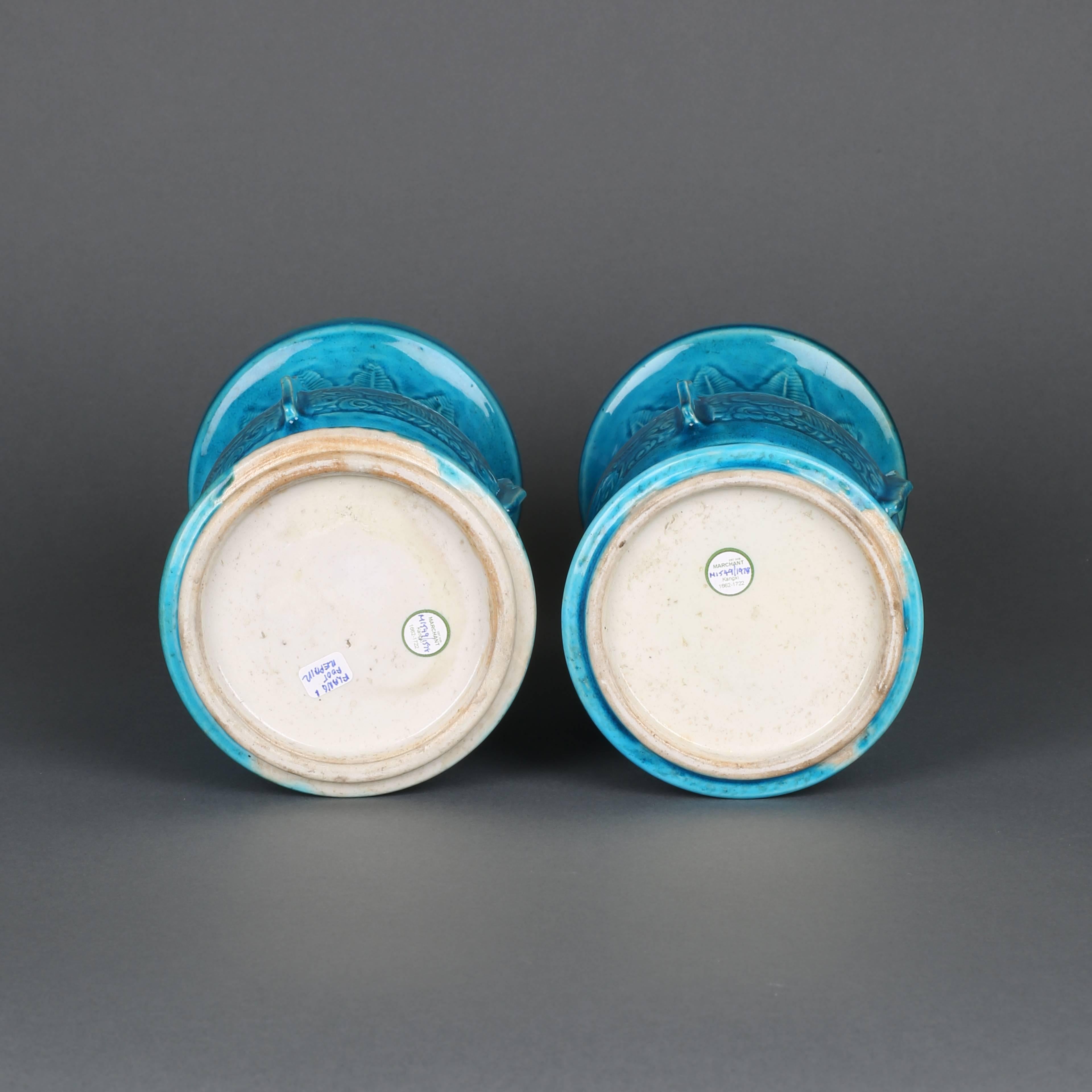A pair of Chinese porcelain turquoise glazed vases of gu form, each carved with a continuous plantain leaf design on the lower and upper bodies, between a central bulge carved with four panels of chrysanthemum flowerheads on leafy reserves divided