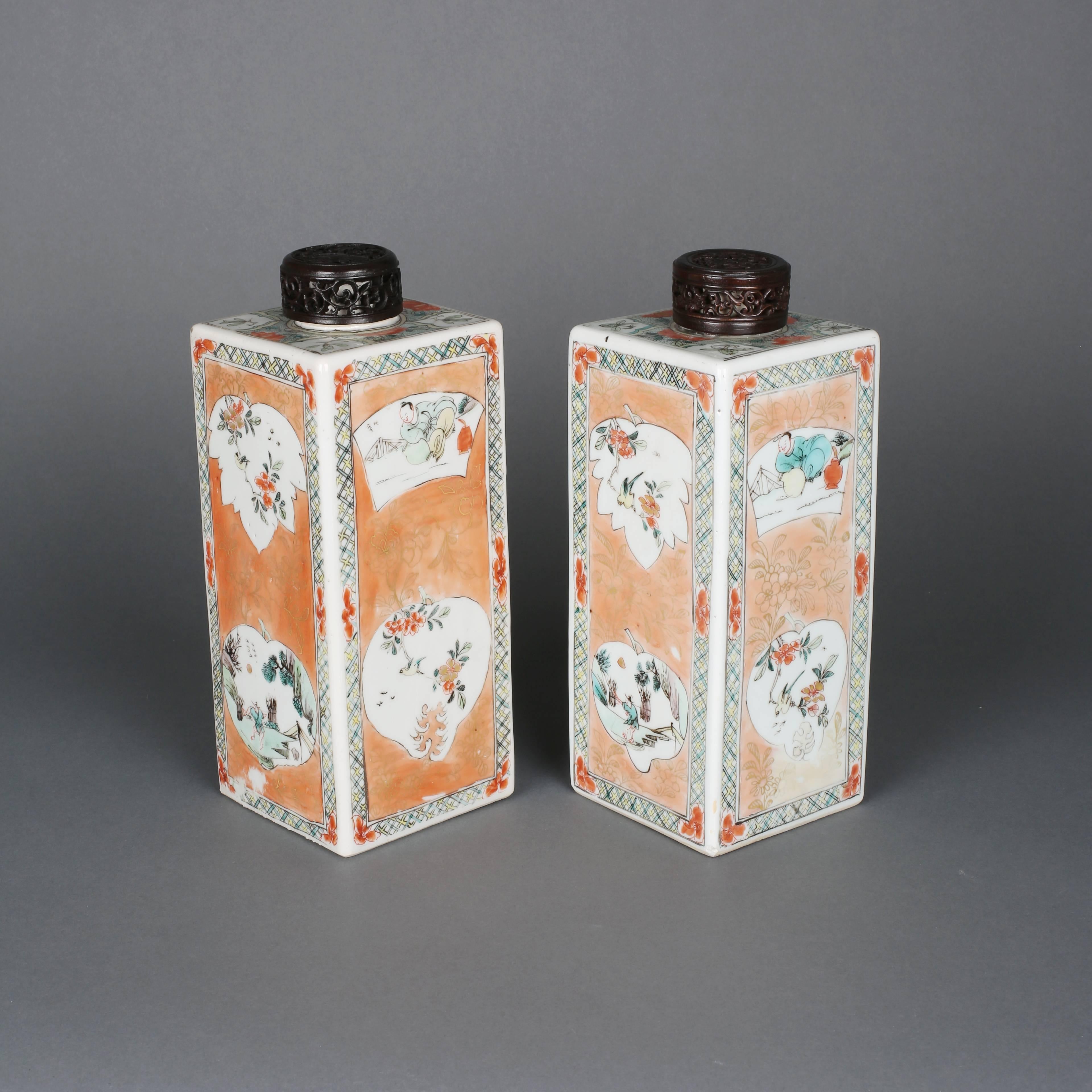 A pair of Chinese porcelain famille verte square tea caddies, painted on the four sides with panels of leaf, scroll, gourd and fruit shapes enclosing scenes of birds and figures, with a continuous border of keyfret divided by six flower heads on the