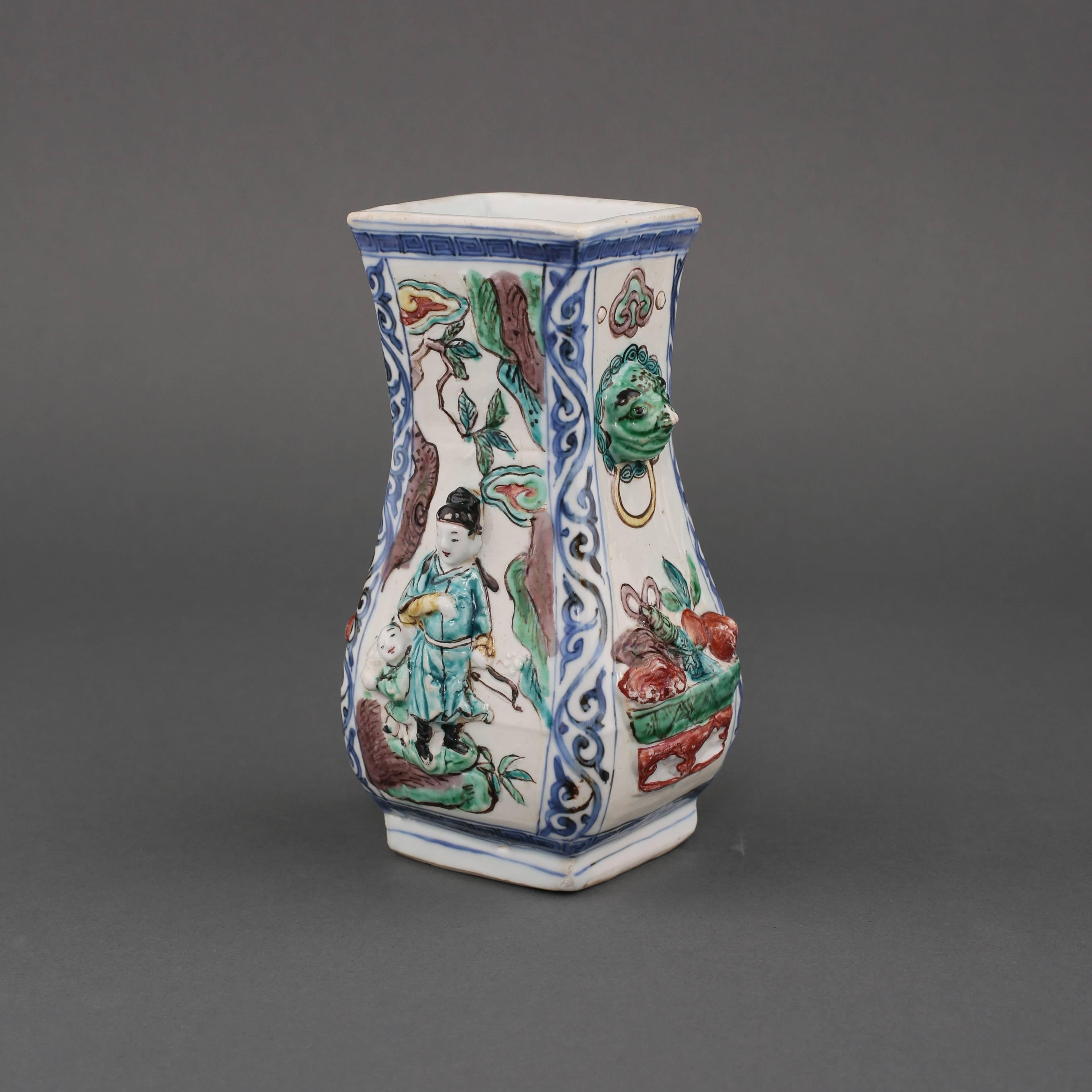 A Chinese porcelain wucai and underglaze blue and white pear shaped rectangular vase with two animal masks and rim handles, moulded on each side, one with a bearded man standing next to a Buddhist lion on rockwork, beneath a pine tree and the moon,