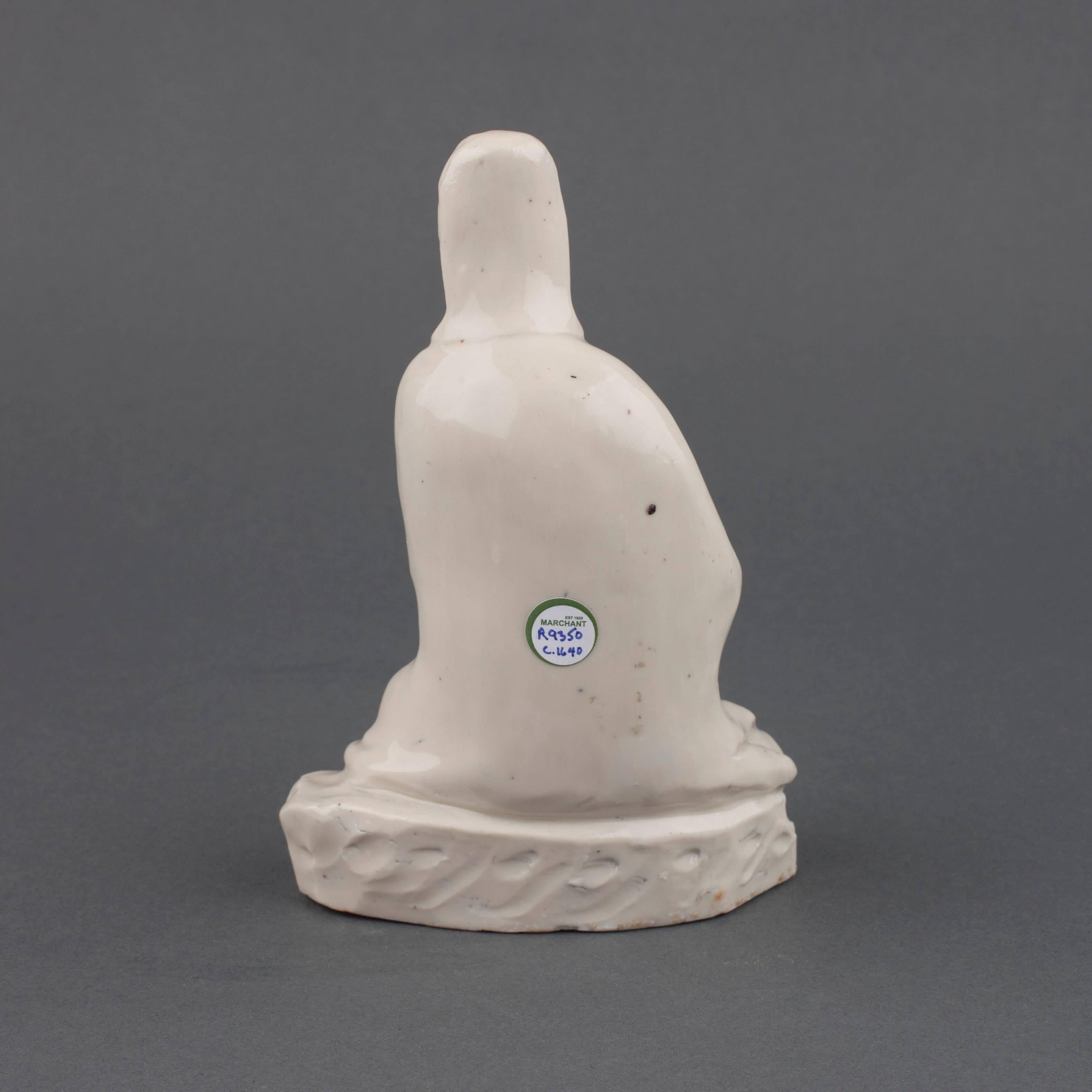 A Chinese Blanc de Chine porcelain figure of a seated Guanyin, her hands together resting on her right raised knee, she wears long flowing robes with tall cowl revealing her high-piled hair, all on a rock work base,

circa 1640.

Measures: 15cm
