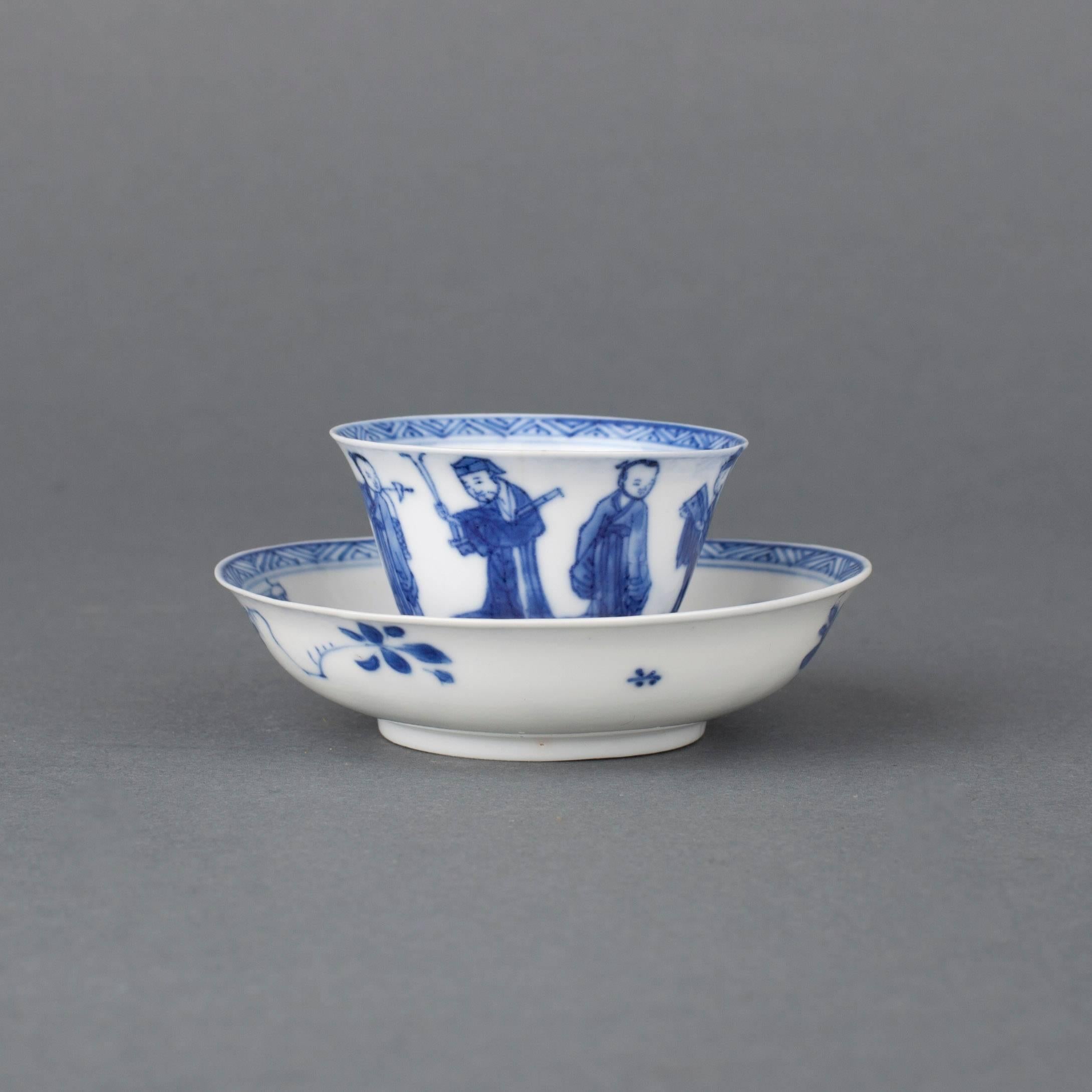 A Chinese semi-eggshell porcelain blue and white miniature tea bowl and saucer with flared rims, the cup painted on the exterior with the Eight Immortals, the interior well with chrysanthemum within a double ring, the inner rim with diaper band,