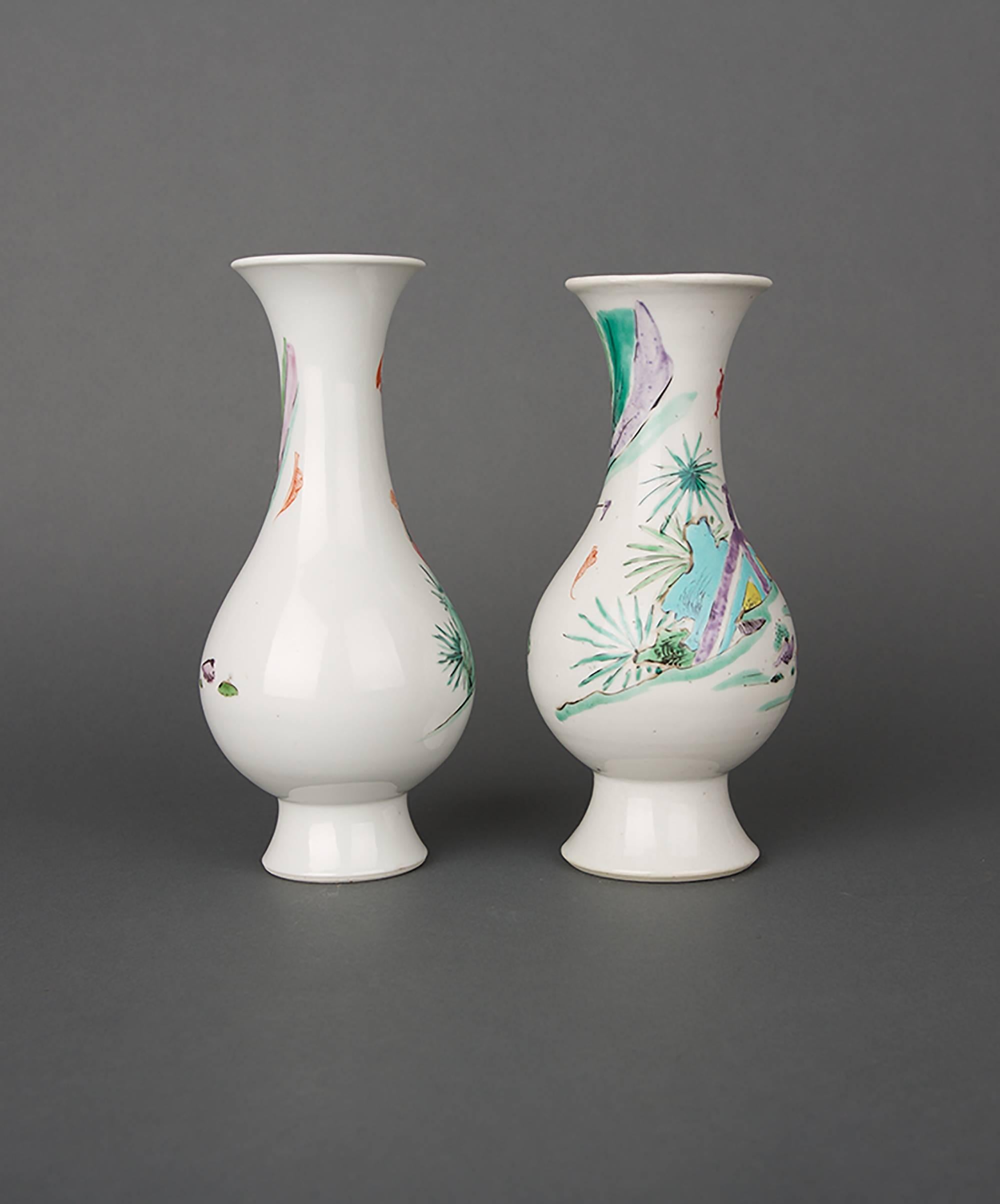 A pair of Chinese porcelain famille rose bulbous vases with gently flared mouths on tall splayed feet, one painted with a man and boy carrying a basket in a fenced riverscene, the other with a man and boy in a landscape with iron-red bat flying