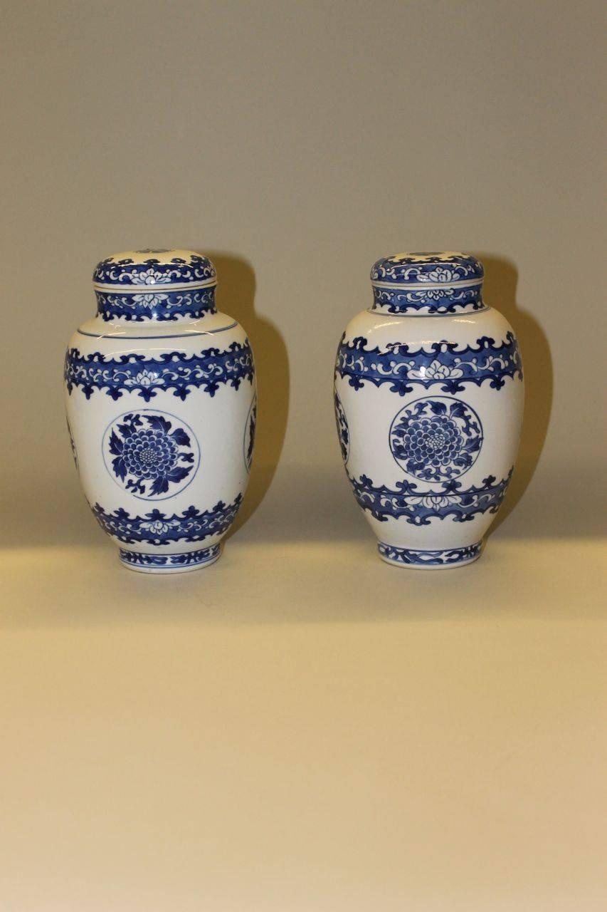A pair of Chinese porcelain blue and white ovoid jars and covers each painted with four chrysanthemum flower head medallions between bands of demi flower heads and scrolls on a blue ground, the covers painted with a stylized mallow flower head above