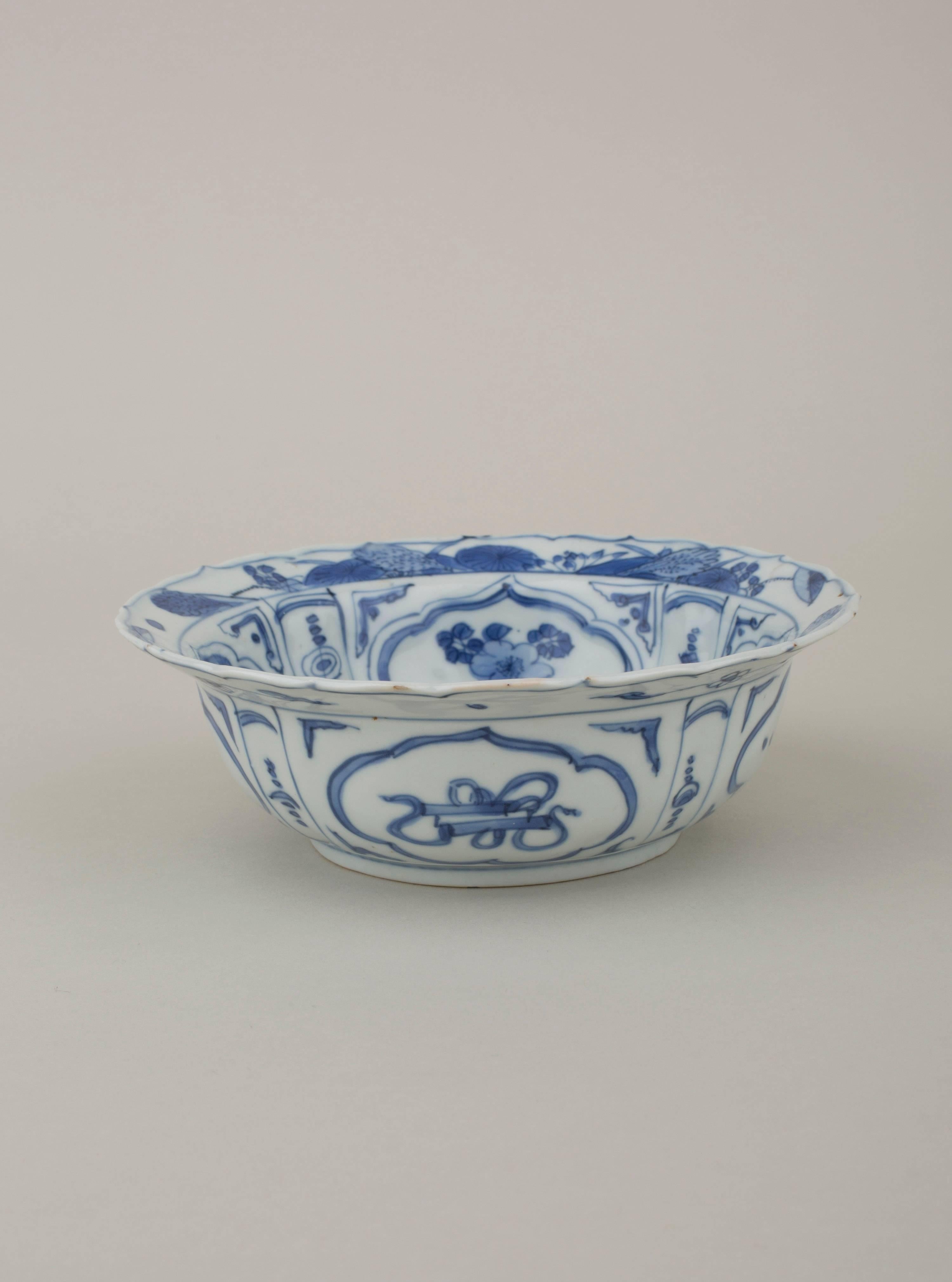 Chinese porcelain blue and white kraak klapmutz bowl with foliate everted rim, painted in the centre with a mountain landcape scene with pagodas and flags, the cavetto with with four panels of flowers, divided by flower panels, a futher continuous