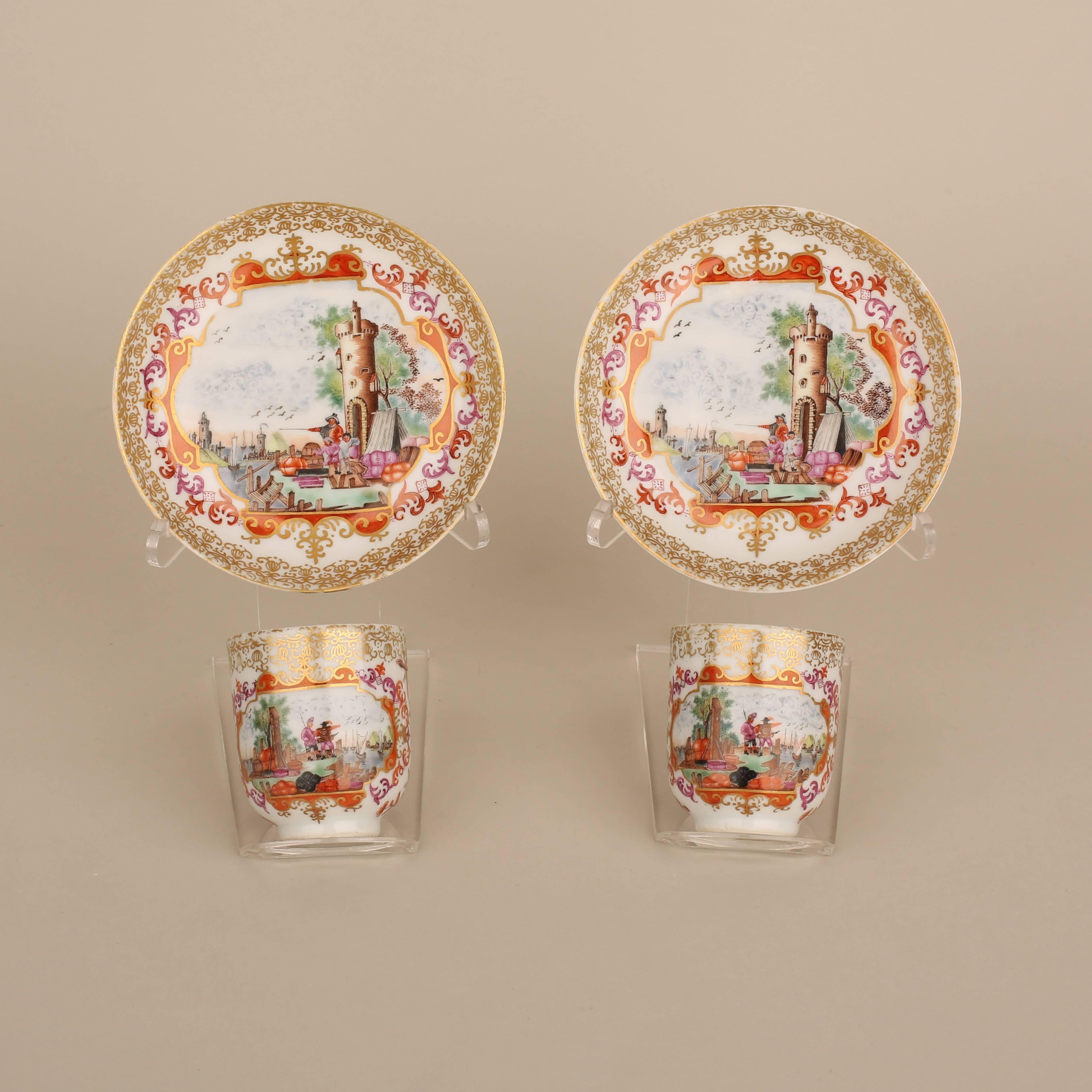 A pair of Chinese porcelain eggshell European subject cups and saucers painted in enamels with a central shipping scene with three figures next to a watch tower overlooking a port, enclosed by a decorative orange, pink and gilt border, further