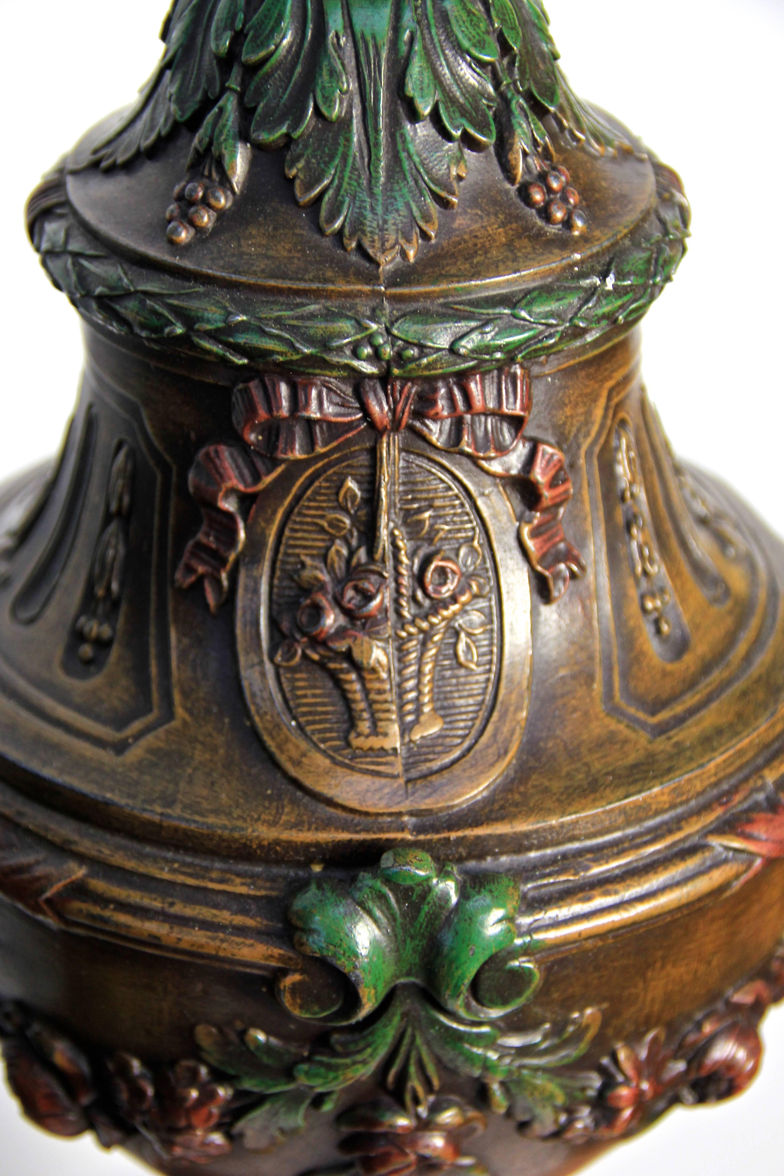 The floral ornamentation combined with the bronzed metal shows the typical style of the Art Nouveau era. Sitting on red marble bases with small golden feet, these pair is an eye-catcher. The closed design of this metal urns fits perfect to a Classic