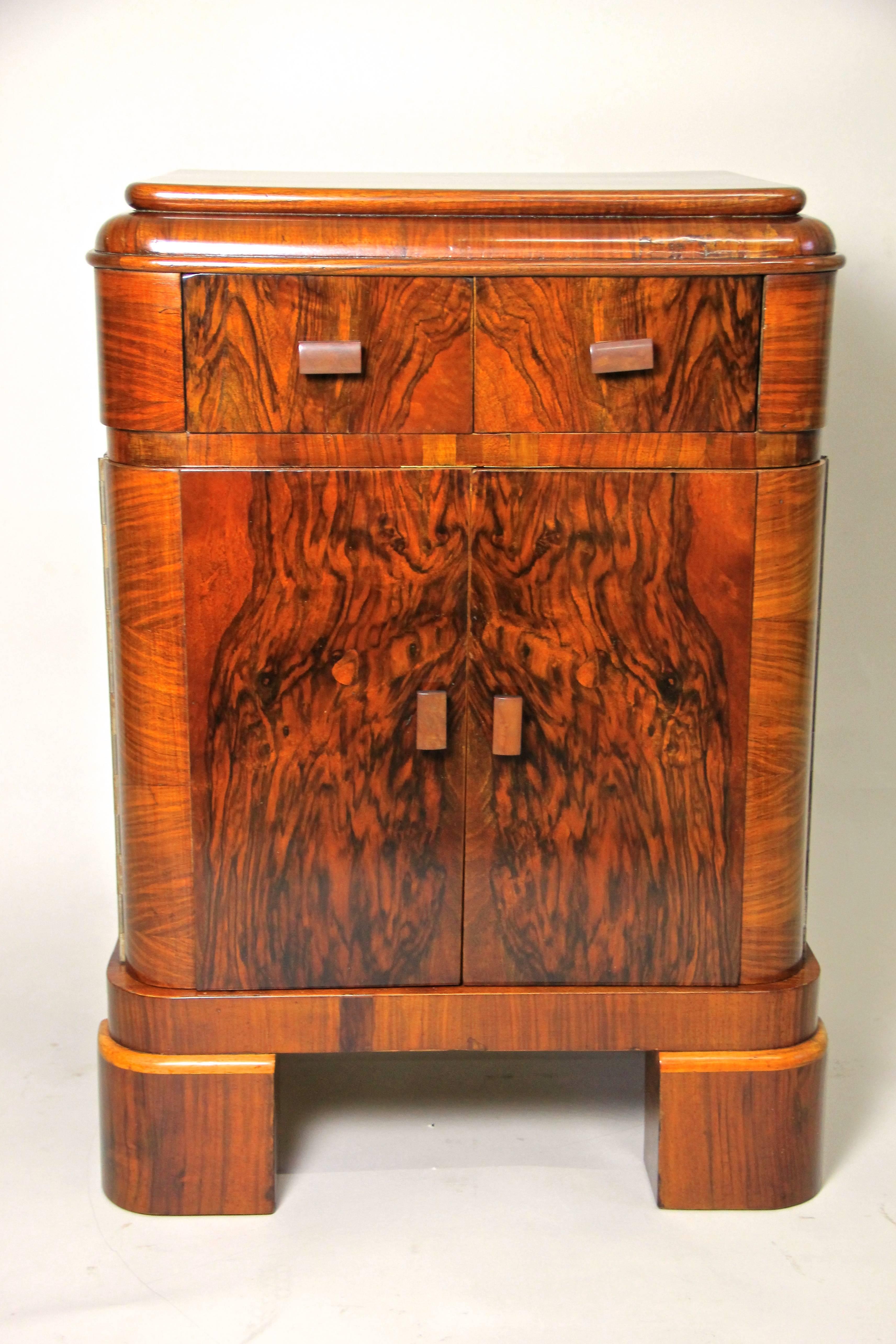 From the Art Deco era in Austria, circa 1925 comes this beautiful small Art Deco chest or side cabinet.
It shows a wonderful veneer picture made of fine burl nut. This fine chest has two small drawers and a double door, all veneered with mahogany