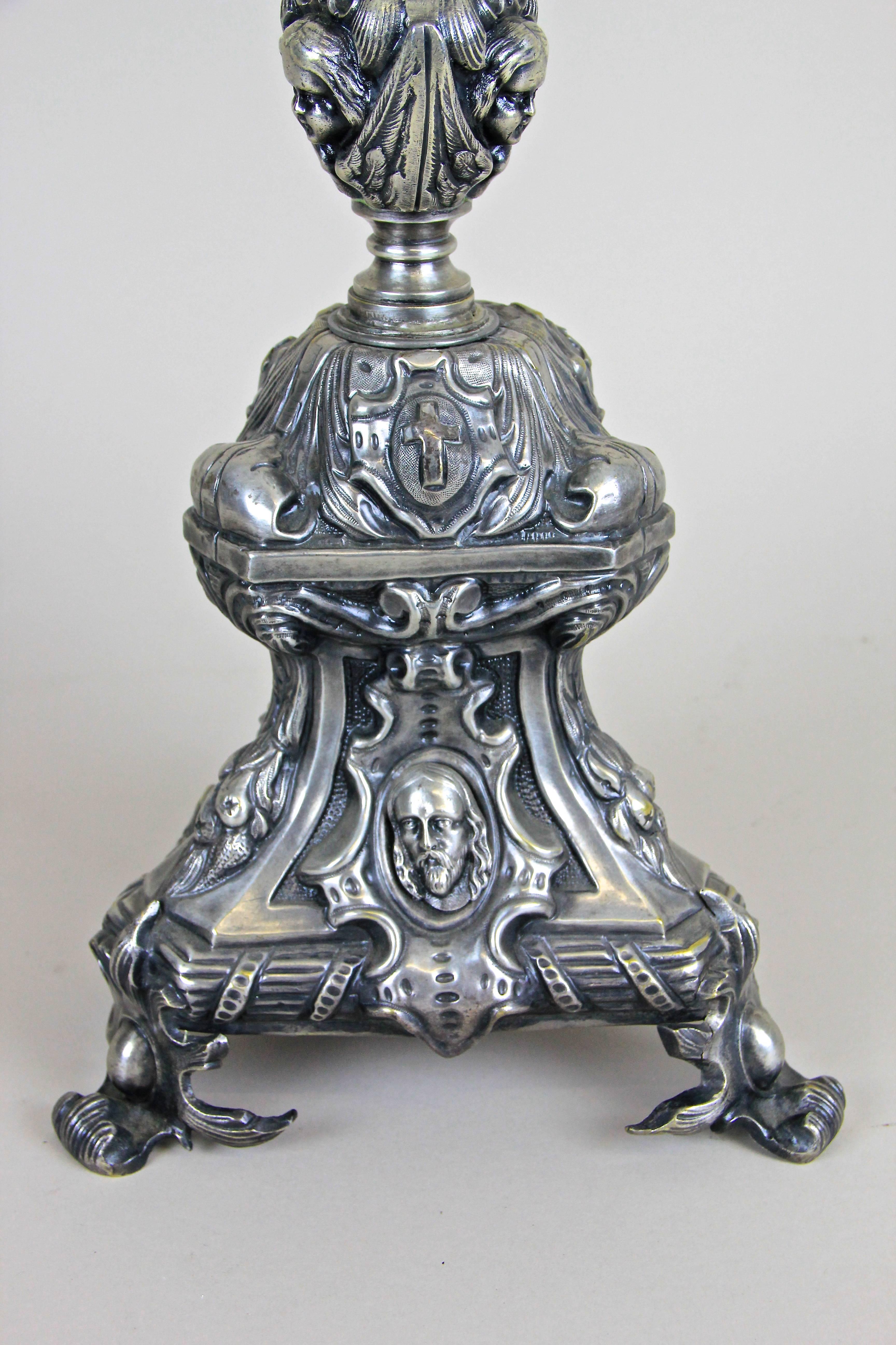 Made of brass with high attention to details, this tall silvered candleholder originated from Austria around the Mid19th century, circa 1850. On each side the main focus lies on three different faces (pictures 2-4) but just take a detailed look on