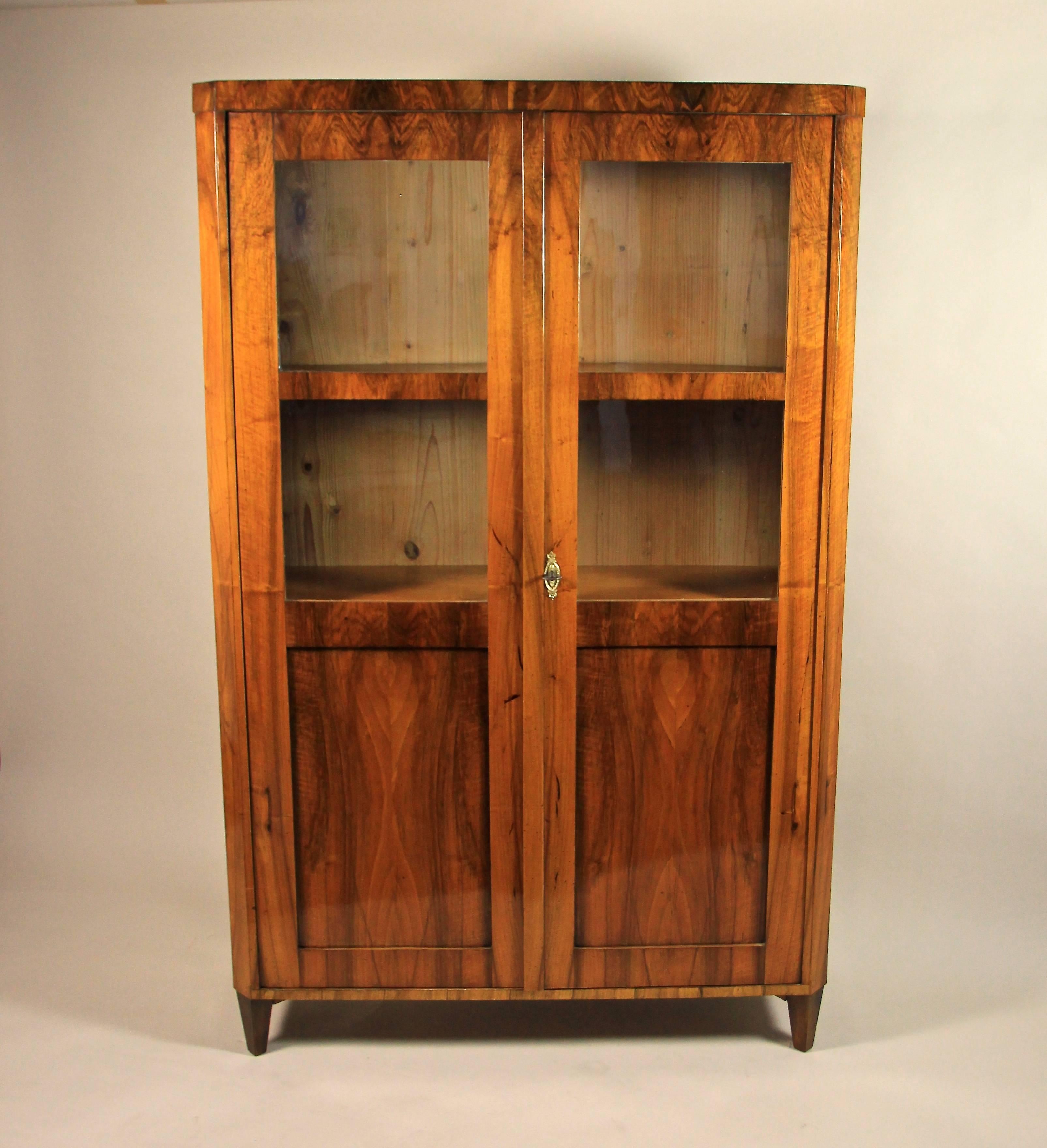Fine Biedermeier bookcase veneered in wonderful burr walnut wood that shows an amazing veneer picture from the top down to the floor. The front of this Biedermeier Bookcase features two doors with two glass panels each. And please also note that