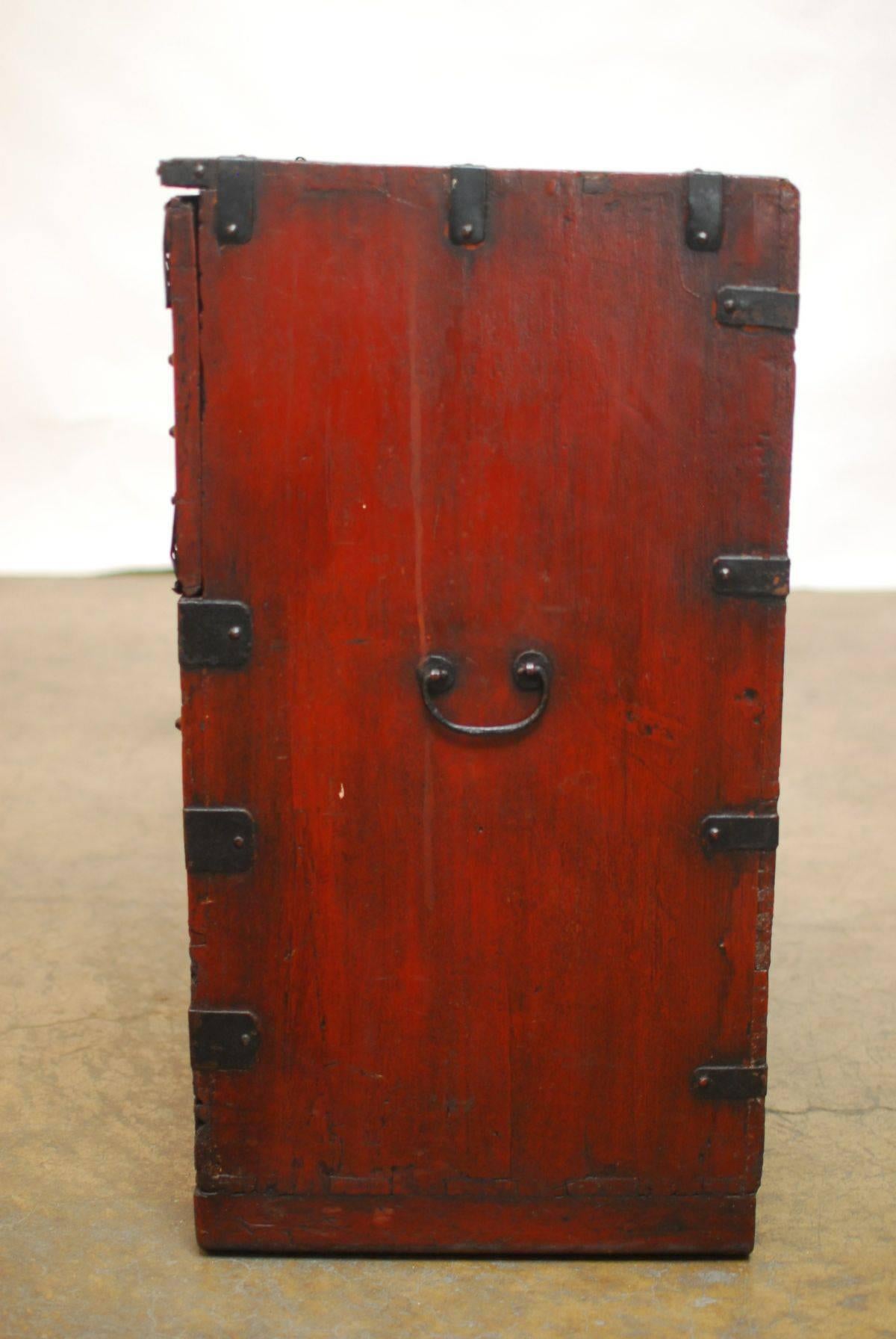 19th century Bandaji chest made in the Kyonggi province featuring a heavily decorated case with wrought iron pierced grill work and iron handles. This rare blanket chest is similar to a Japanese Tansu chest and is finished in a reddish brown lacquer