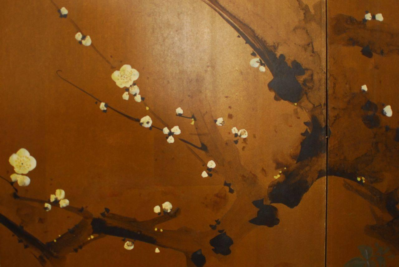 Japanese painted gold leaf screen depicting a cherry blossom tree landscape with ducks swimming by. Intricate detail and subtle shadows convey an idyllic scene. Bordered with a light silk brocade and framed in an ebonized lacquer wood with dark