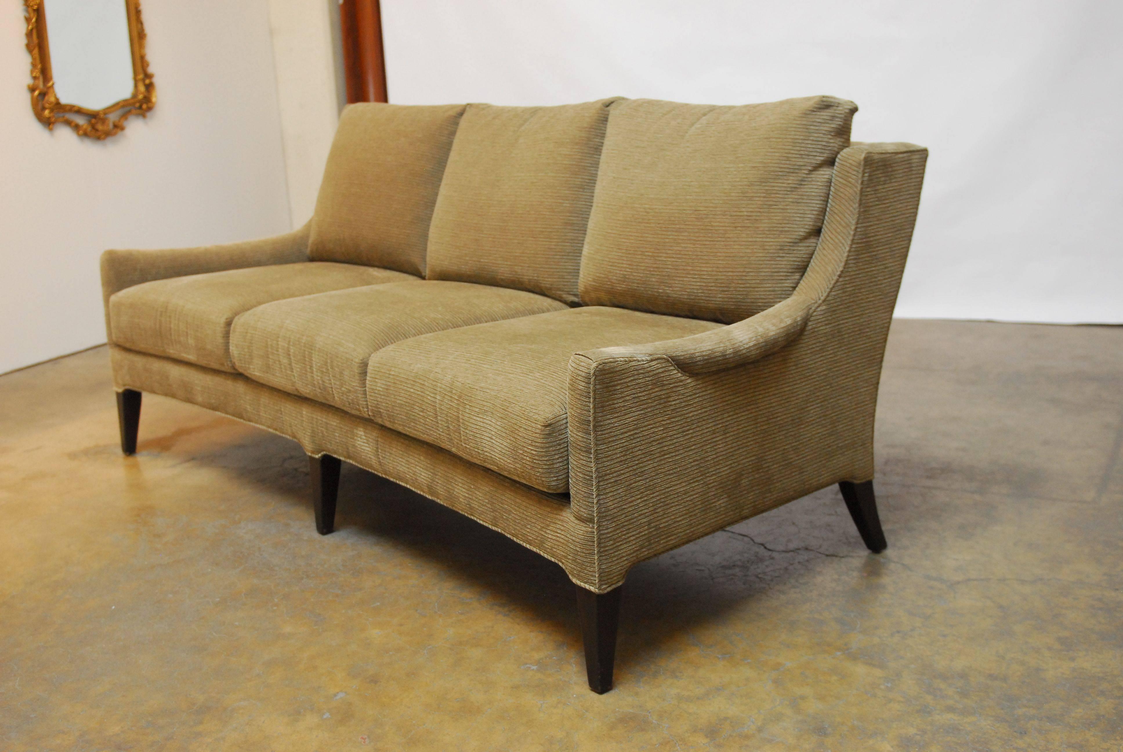 Sculptural sofa with a curved front. Handmade in the U.S. by Kravet in the Mid-Century Modern style. Constructed with a deep seat and an arched back with splayed rear legs and tapered front legs finished in an ebonized wood. Upholstered in a rich