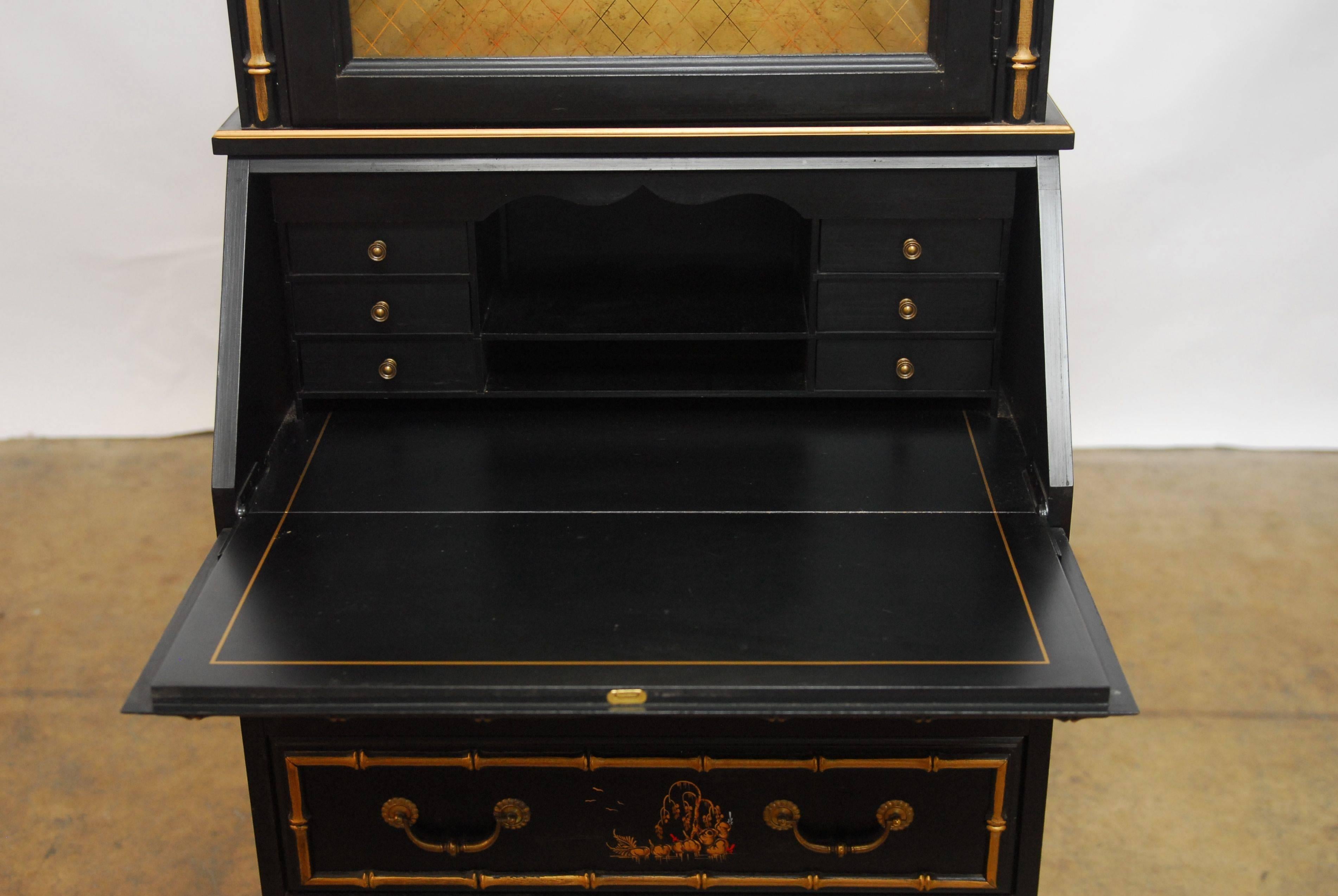 Distinctive secretary bookcase made in the Chinese taste featuring a decorative gilt faux bamboo trimmed case with hand-painted asian scenes. The domed top has a lighted interior with two glass shelves and a locking concave glass door with fine gilt