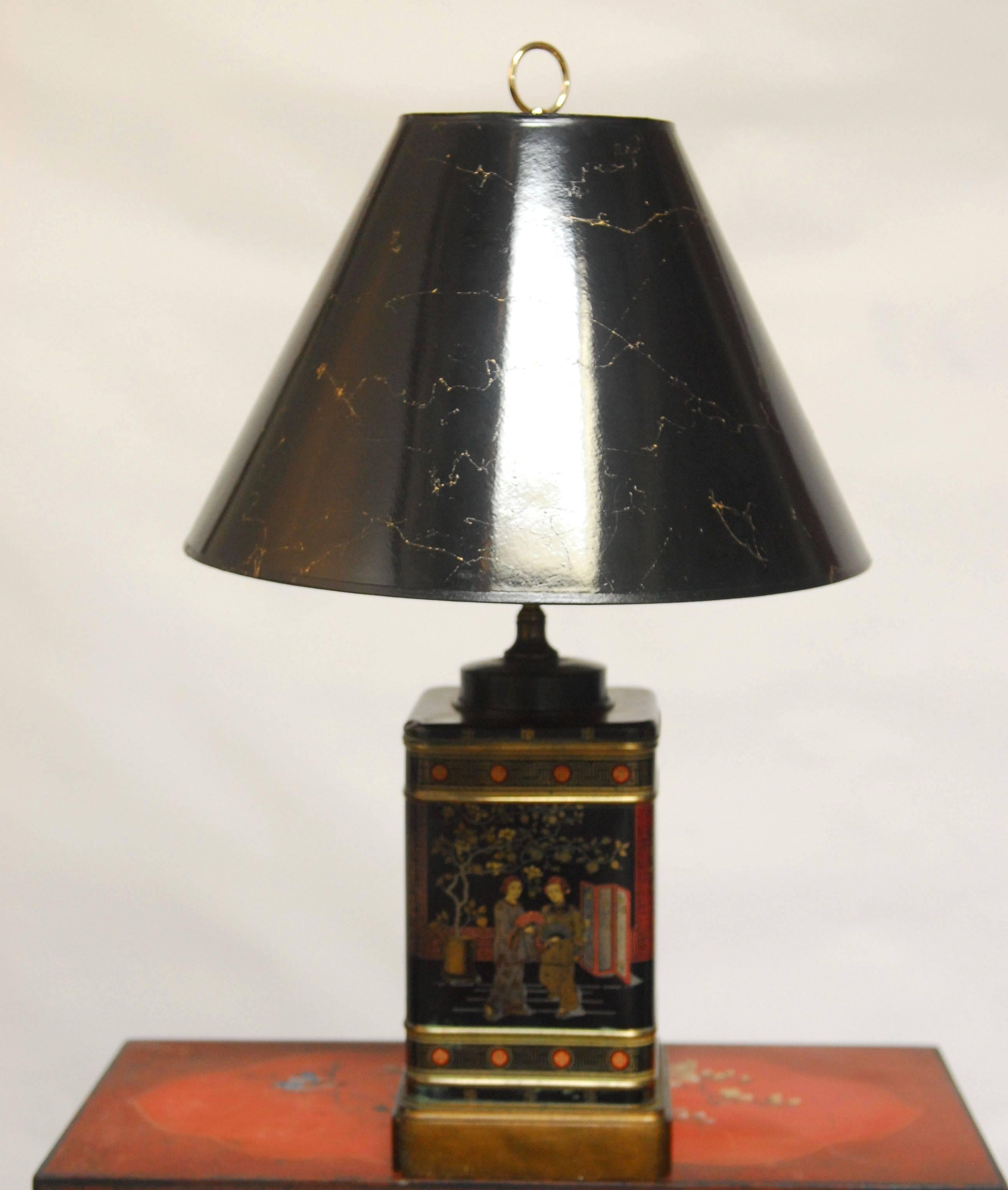 Black tea canister table lamp mounted on a giltwood base featuring different social scenes and brass hardware. Made by Frederick Cooper of Chicago, IL. from an early 1900s tea canister.