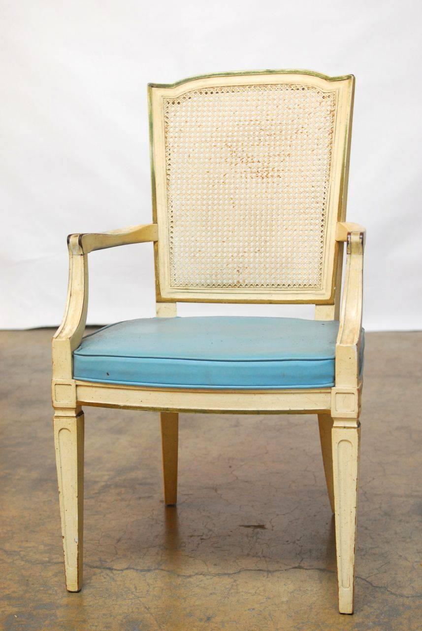 Set of six cane back dining chairs by Henredon featuring a light blue vinyl upholstery and a distressed finish with some of the original green trim accents over a cream lacquer. Set consists of four side chairs and two armchairs. The armchairs