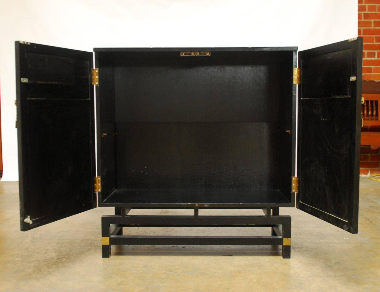 Impressive black lacquer cabinet made with antique parcel-gilt panels mounted onto the two front doors. Intricately carved shrine panels decorated with red lacquer and gilt. The cabinet is supported by an open stretchered Stand with brass accents