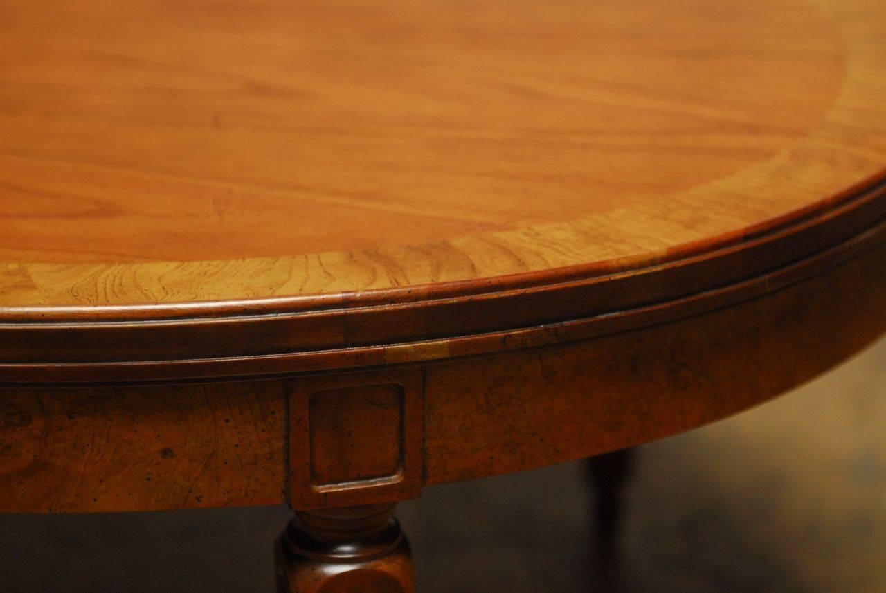 Rich walnut coffee table made by Baker in the Louis XVI style featuring an inlay top of burl wood and an oval form. Supported by tapered, fluted legs and toupee feet. Elegant style and superior craftsmanship. 