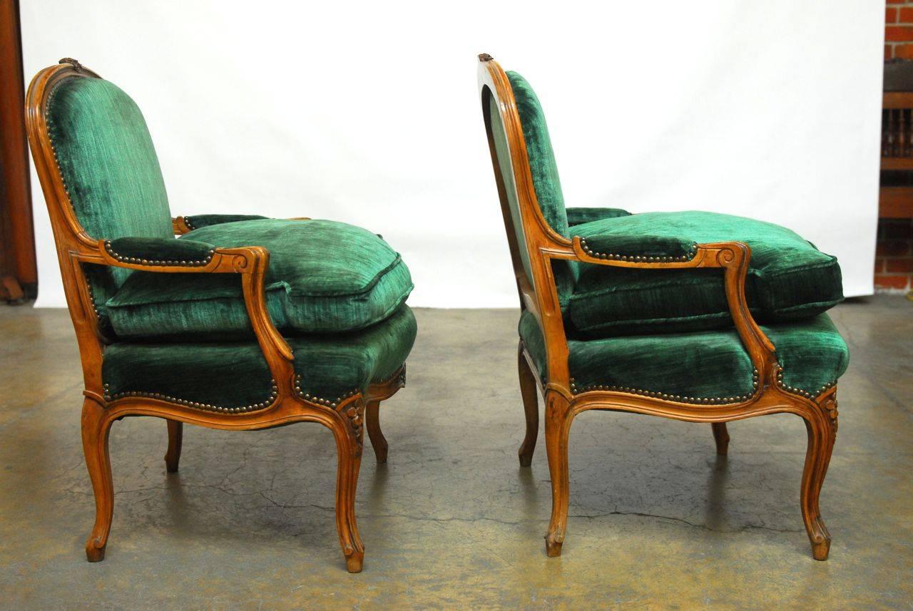 Sensational pair of hand-carved armchairs made in the Louis XV taste featuring a plush velvet upholstery in emerald green. 19th century chairs from France with walnut frames and cabriole legs with a hand rubbed finish. Brass nailhead trim and thick