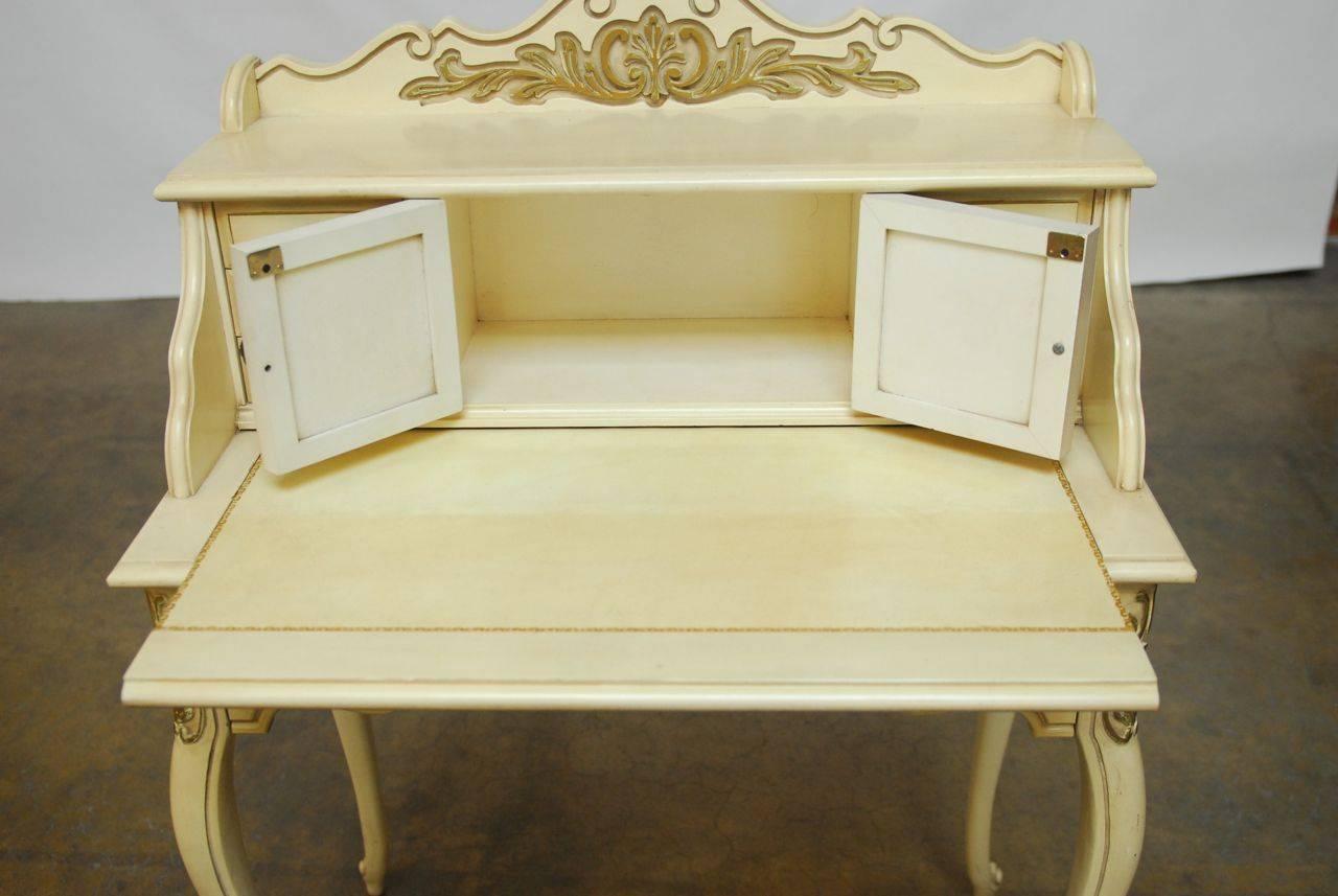 Diminutive ladies writing table made in the French Provincial style with a fitted six drawer storage cabinet. Features a parcel gilt cream lacquer finish and is supported by long tapered cabriole legs and scrolled feet. The desk has a slide out top