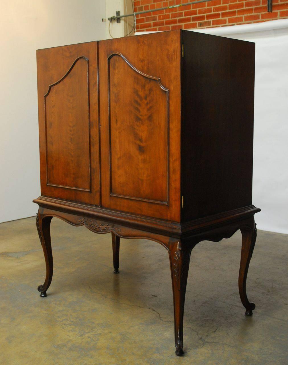 Extraordinary carved walnut cabinet on a carved stand made in the French Louis XV style featuring cabriole legs and scalloped sides. Fronted by two large doors, this cabinet would make a great armoire, desk, or cocktail dry bar. It has a slide out