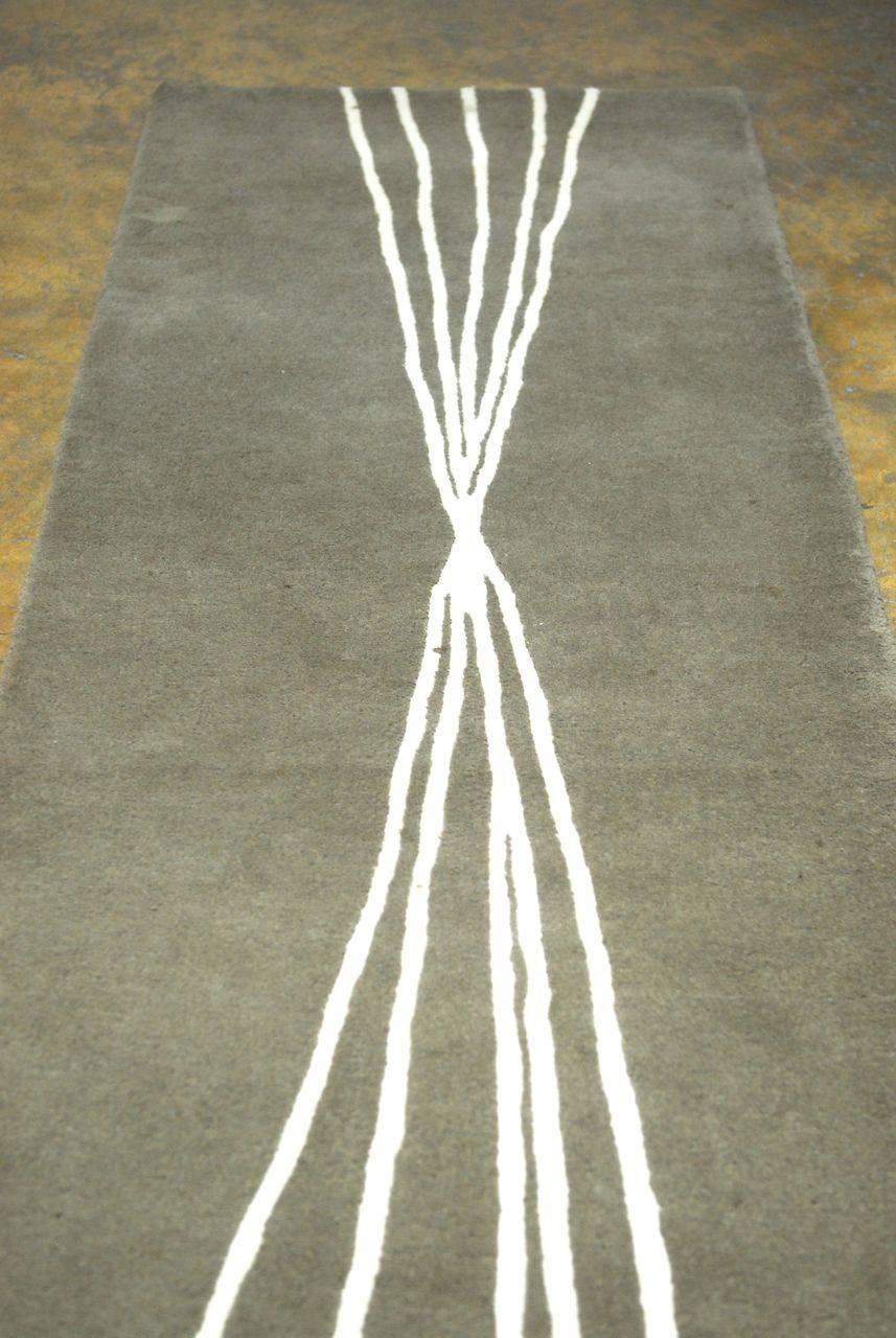 Modern rug with a grey thick wool pile featuring an abstract design of intersecting lines. Machine made runner with an interesting artistic design.
 