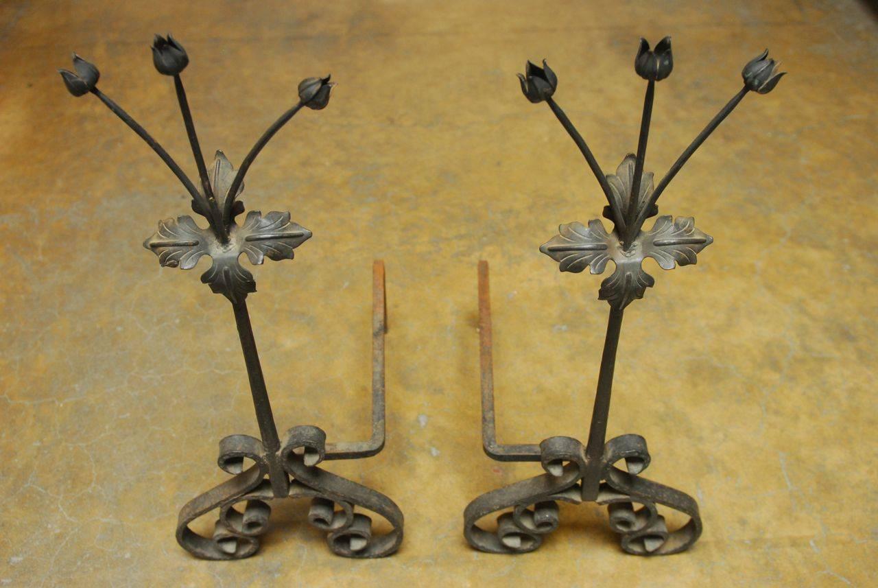 Lovely pair of wrought iron andirons made in France featuring delicate flower buds rising up from Acanthus leaves from a thick round stem. Supported by flat bar scrolled feet with texture pattern on the edges. Heavy, solid and tall these andirons