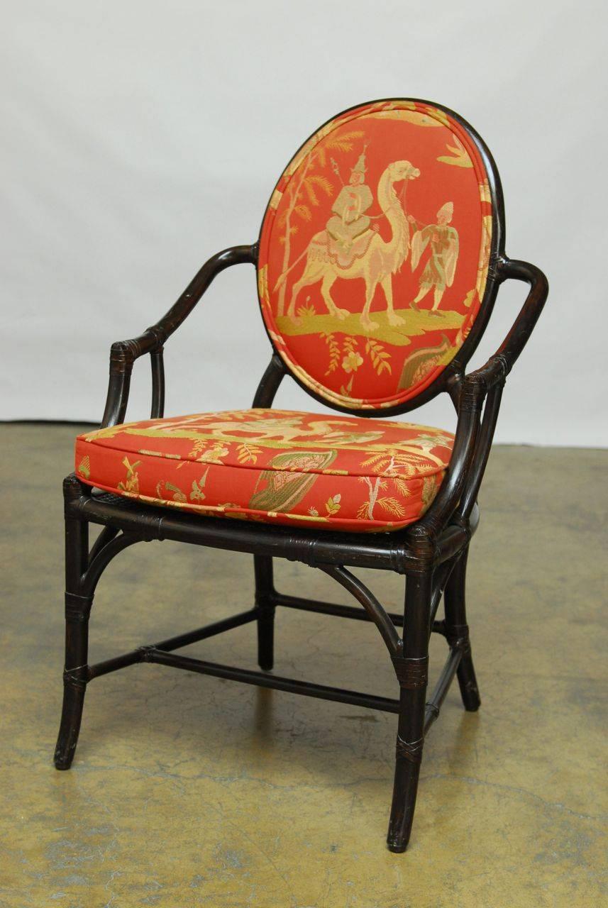 Stunning set of armchairs by McGuire of San Francisco, CA. Featuring an ebonized bamboo rattan frame with rawhide strapping. Made in the Chinese Chippendale taste with a cane seat bottom and an oval form upholstered back. Chinoiserie scenes with a