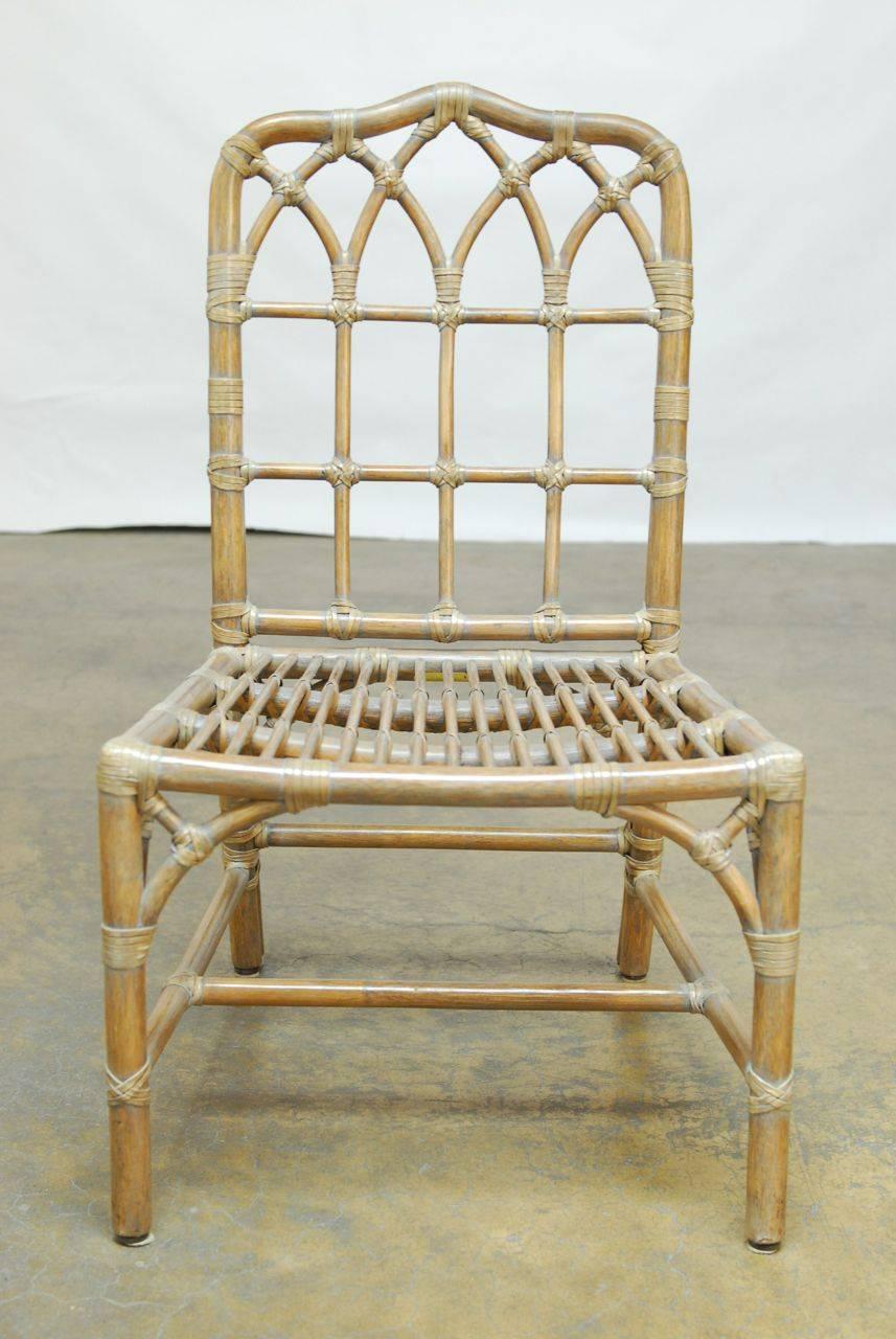 Pair of Chinese Chippendale style bamboo rattan dining chairs by McGuire with rawhide strapping. Cockpen open fretwork back with a shaped crest and a light cerused hand-applied finish. Decorative spandrels finish the look. These chairs are in