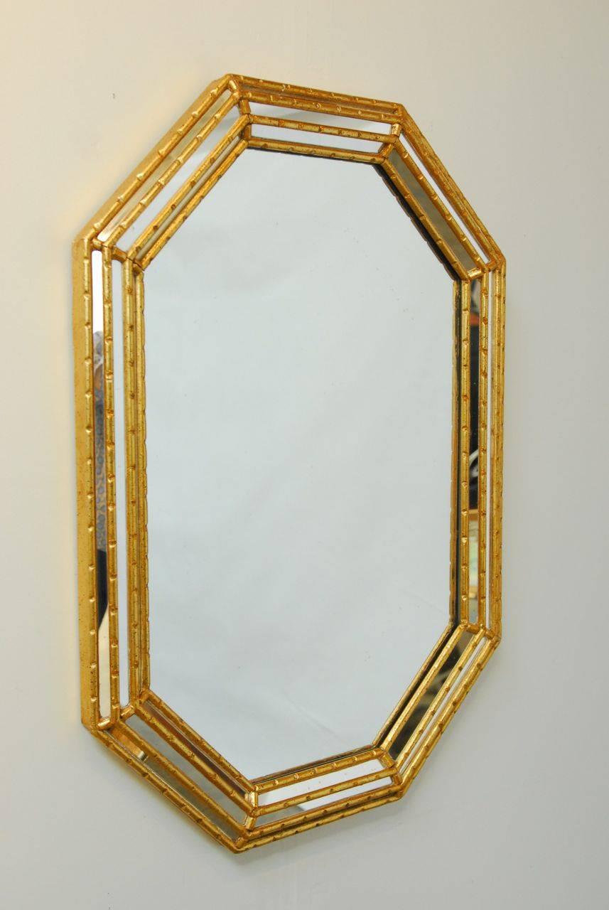 Glamorous Mid-Century mirror featuring a faux bamboo frame made of carved wood with a gilt finish. Octagonal form with a beveled frame that has three layers of decorative angled mirrors.