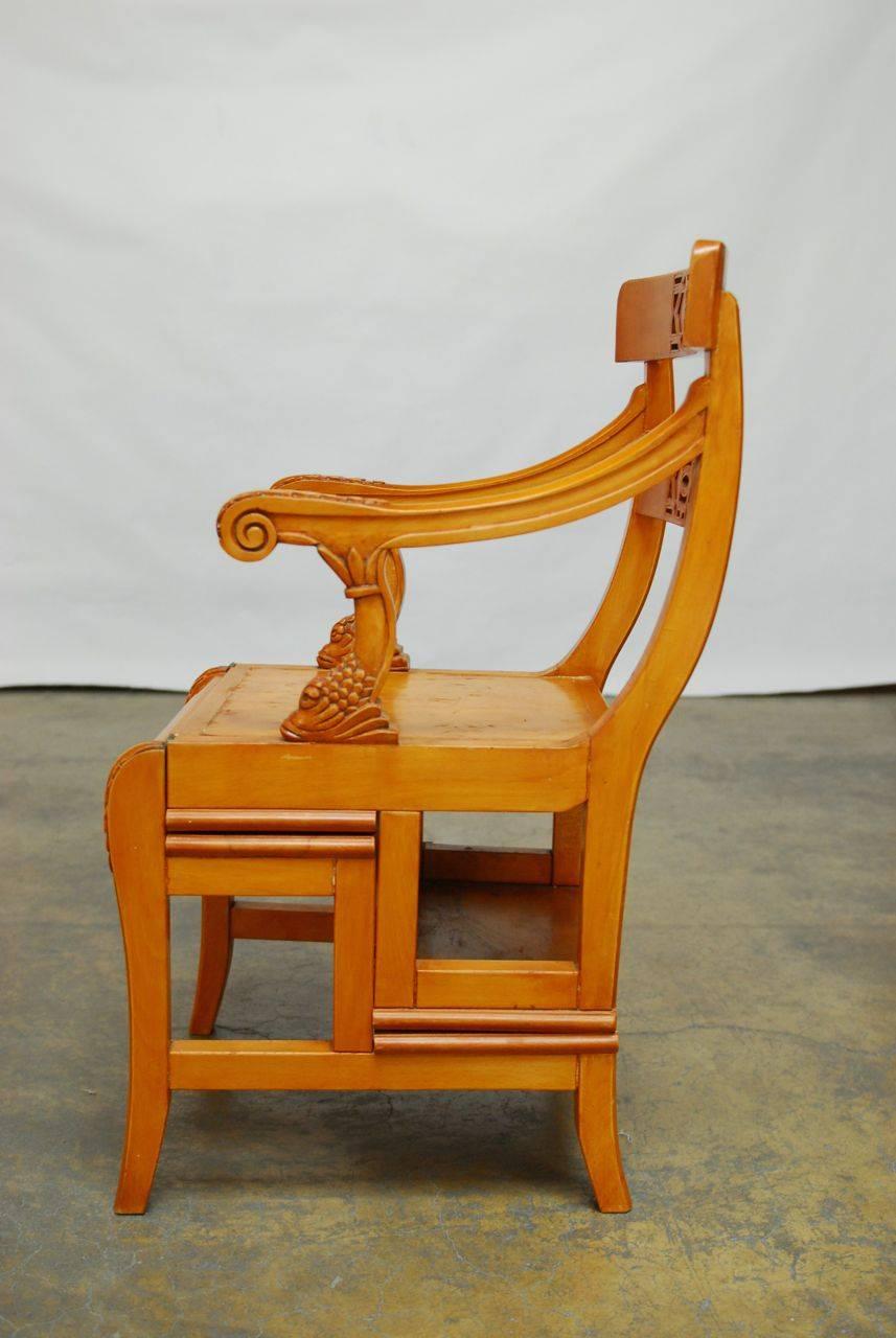 Rare and unique metamorphic library step chair featuring hand-carved dolphin arm supports in a neoclassical taste. This solid colonial chair opens to four steps with a 30