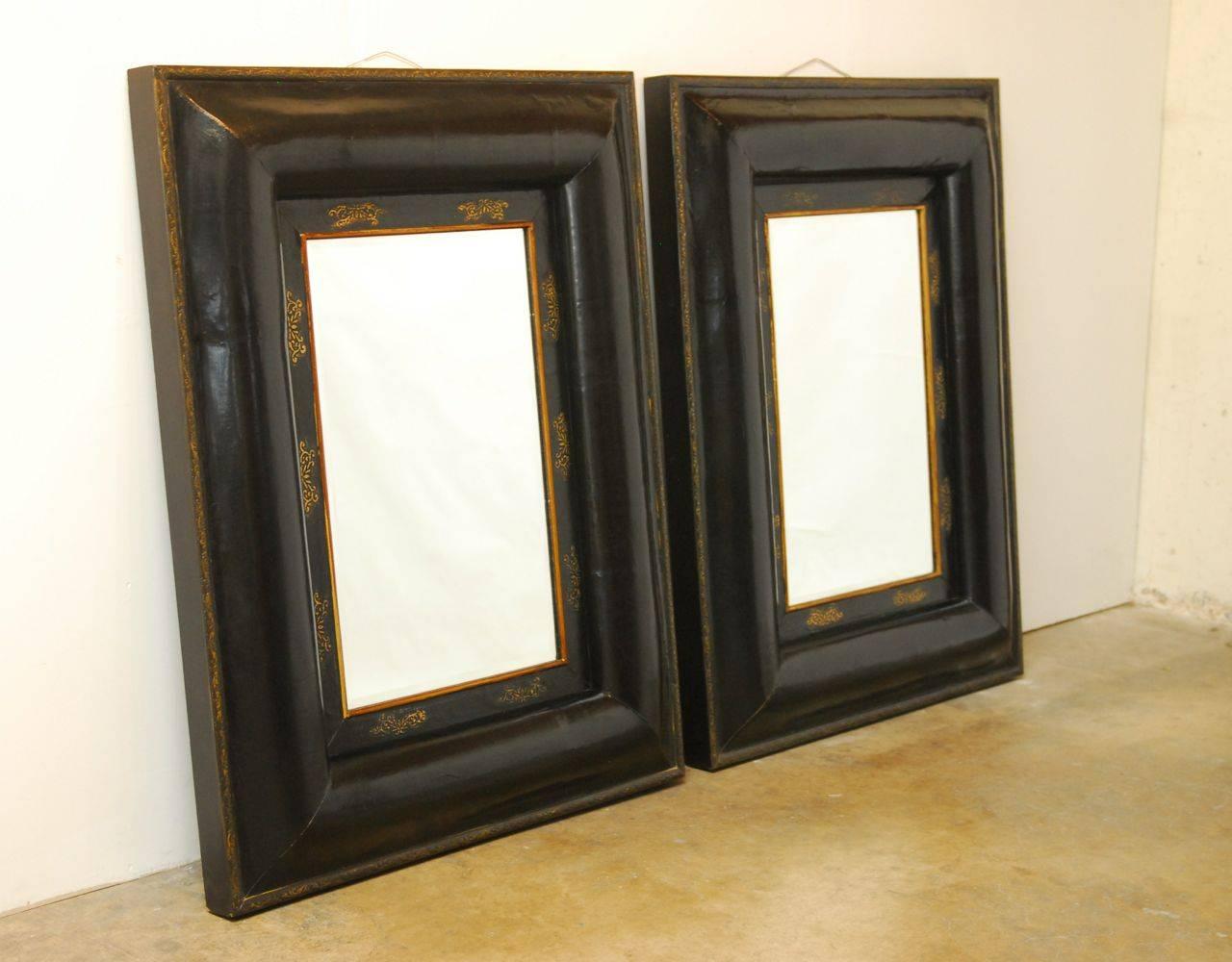 Striking pair of huge ebonized Portuguese mirrors mounted in heavy wooden frames with a beautiful plaster faux finish. Decorated with gilt trim and border with gilt cloud accents around the beveled glass. These lovely mirrors are thick and have a