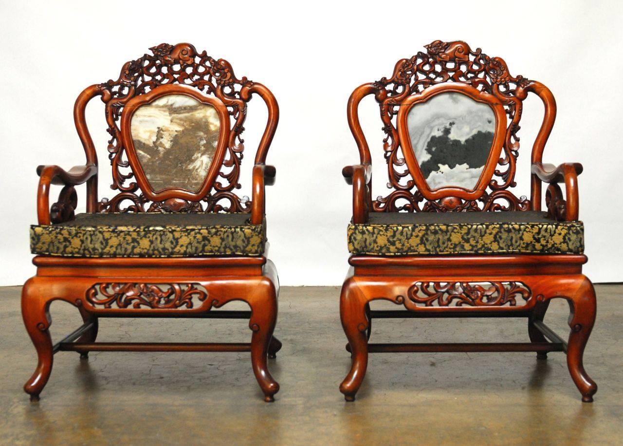 Exquisite pair of hand-carved Chinese armchairs constructed of solid mixed rosewood and Asian hardwood. High relief carvings of dragons, mythical beasts, phoenix, and decorative elements. Centered on the back by Chinese marble Dali or dreamstone