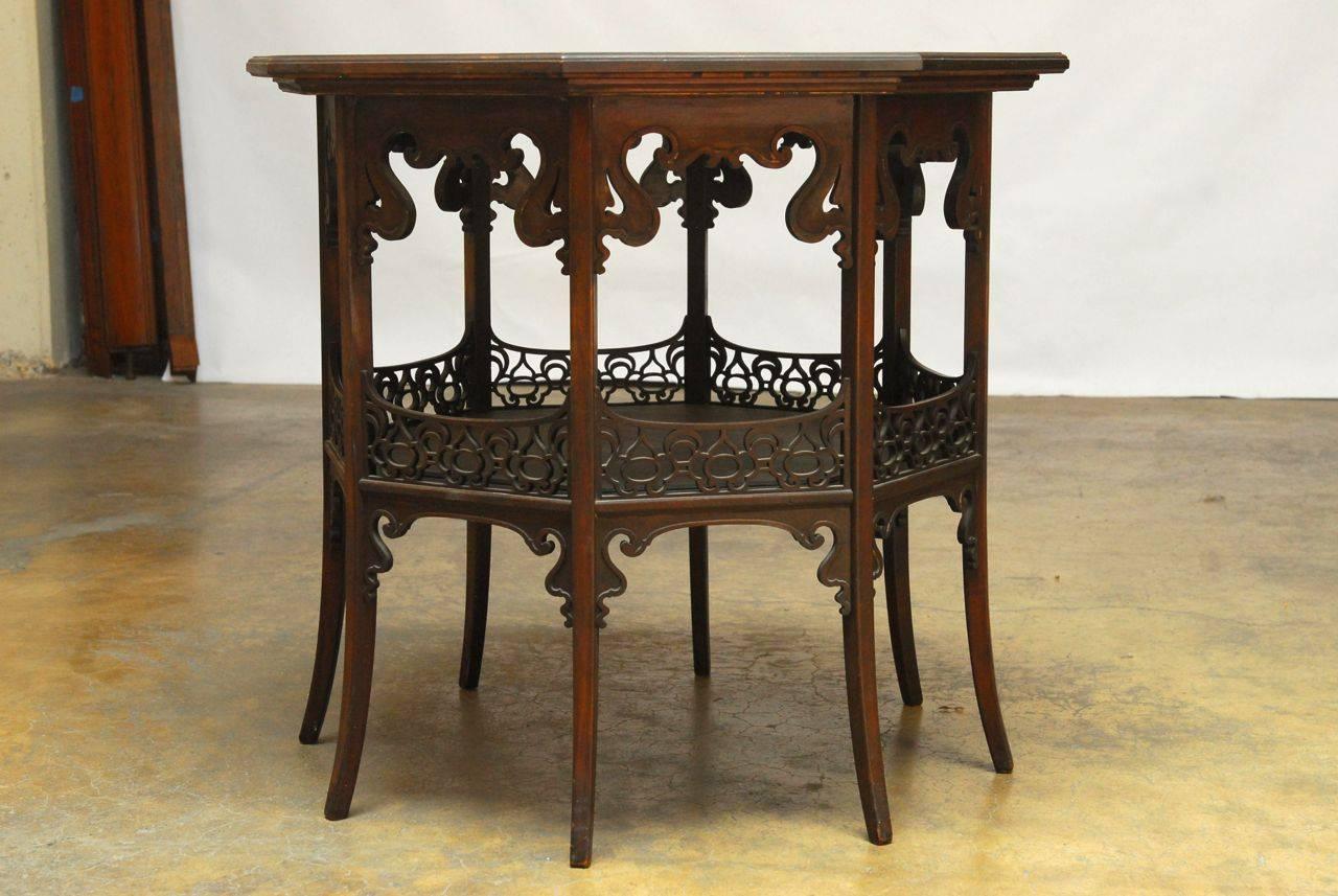 Sophisticated Persian center table with ornate relief carving to the top and a pierced lattice fretwork apron on the lower shelf. Scrolled spandrels give a dramatic arch appearance throughout the piece and showcases a Moorish influence. Supported by