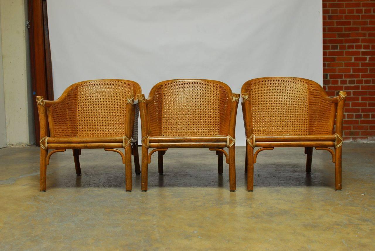 Set of supremely comfortable lounge chairs featuring a luxurious double layer of wicker caning affixed to a bent bamboo frame. Sleek barrel back design armchairs reinforced with rawhide strapping. Price of for all three each is signed on bottom.