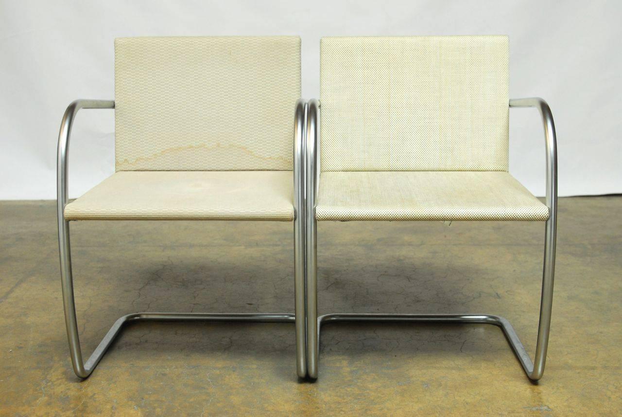 Sleek pair of thin pad Brno chairs featuring a brushed nickel finish. Each chair is signed under the arm. Tubular steel frames in a cantilever style. Fabric on both chairs is stained.